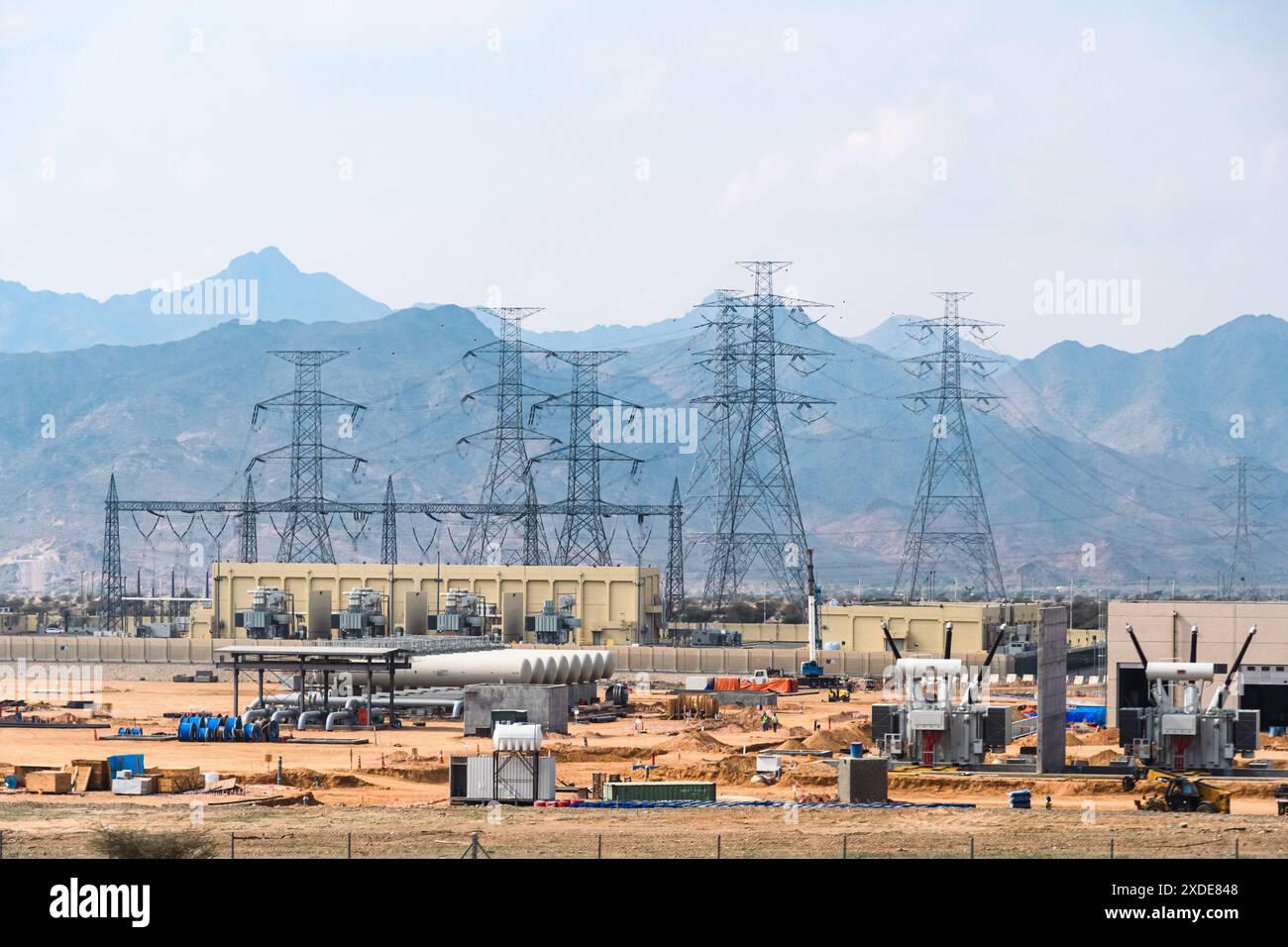 Medina, Saudi-Arabien - 22. Dezember 2022: Industrieller Fortschritt durch Stromleitungen gegen Bergsilhouetten. Stockfoto