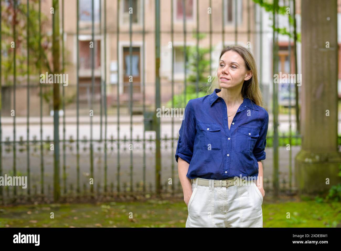 Eine lächelnde Frau mit blauem Hemd und weißer Hose genießt ihre Zeit im Freien. Stockfoto