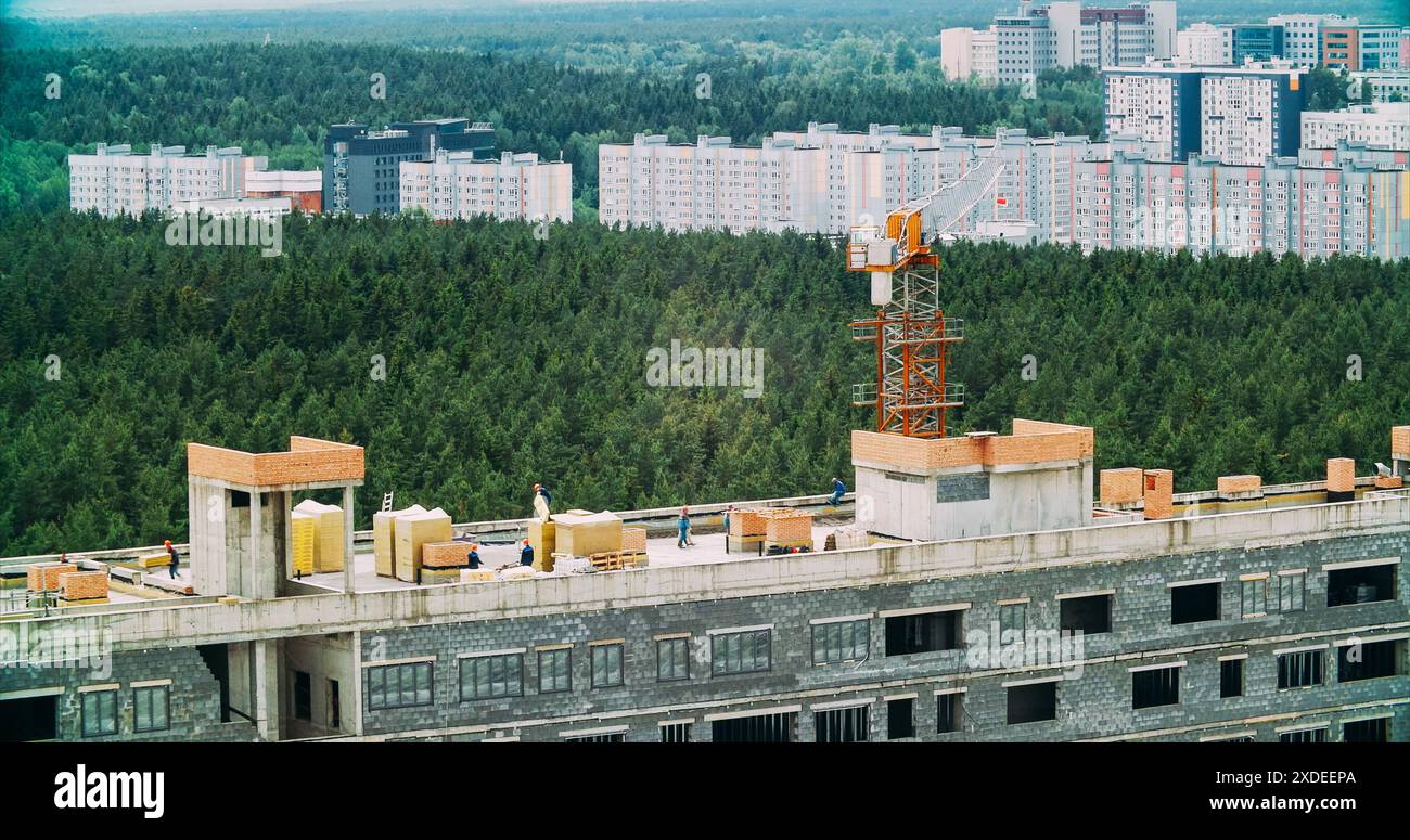 Construction Crane ist am Bau Eines neuen mehrstöckigen Wohnhauses beteiligt. Kran Im Einsatz. Konstruktion Und Entwicklung Neuer Multi Stockfoto