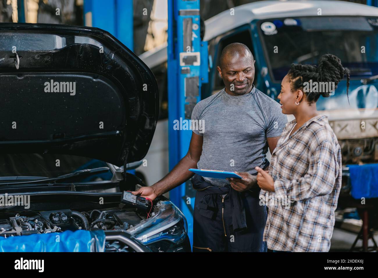 Mechaniker, der mit Frauen spricht, Kunden informieren, erklären Fahrzeugproblem, Service-Details in der Garage. Stockfoto