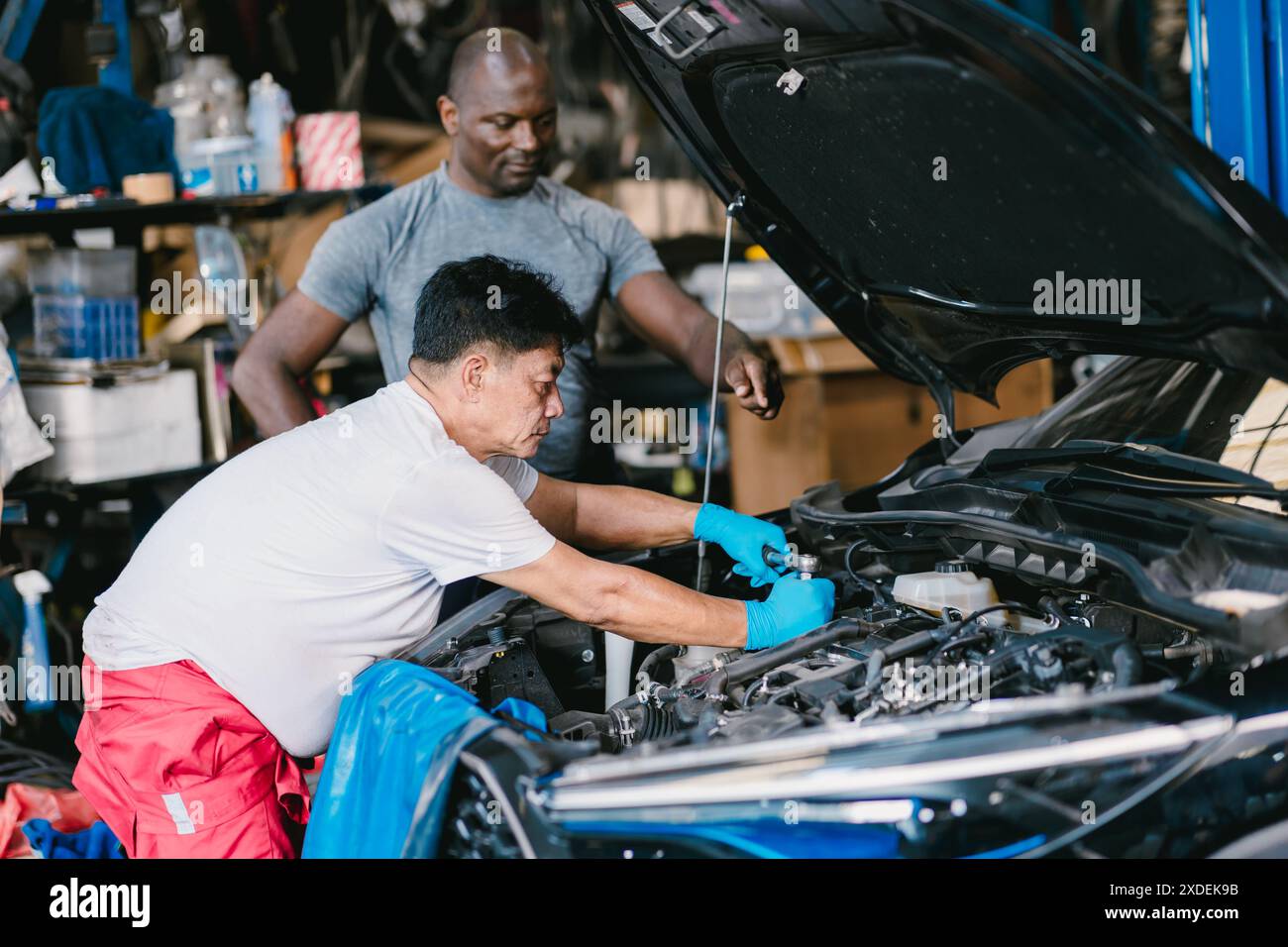 Mechanikerteams arbeiten zusammen, um Motorprobleme in der Autowerkstatt zu beheben Stockfoto