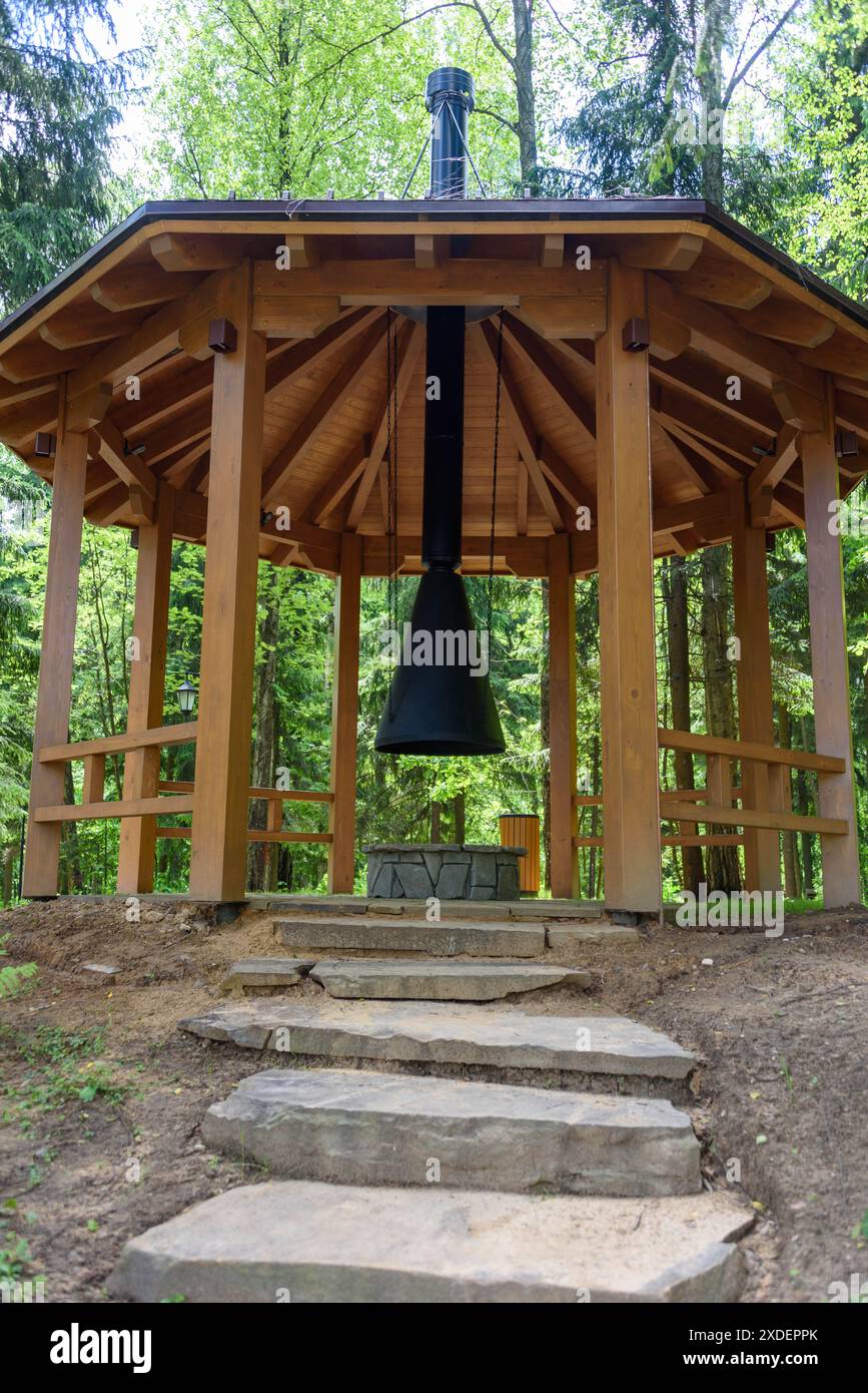 Steintreppen führen zu einem hölzernen Pavillon mit einem Grill und einem Kamin. Ein Spaziergang durch den Park. Stockfoto