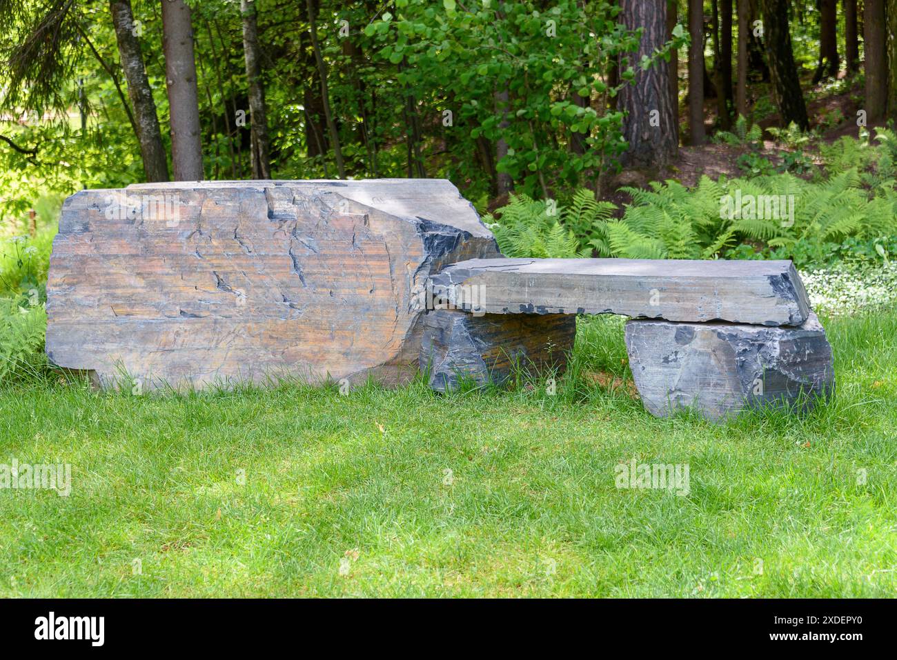Eine Steinbank zum Ausruhen auf dem Parkrasen. Ein Spaziergang durch den Park. Stockfoto