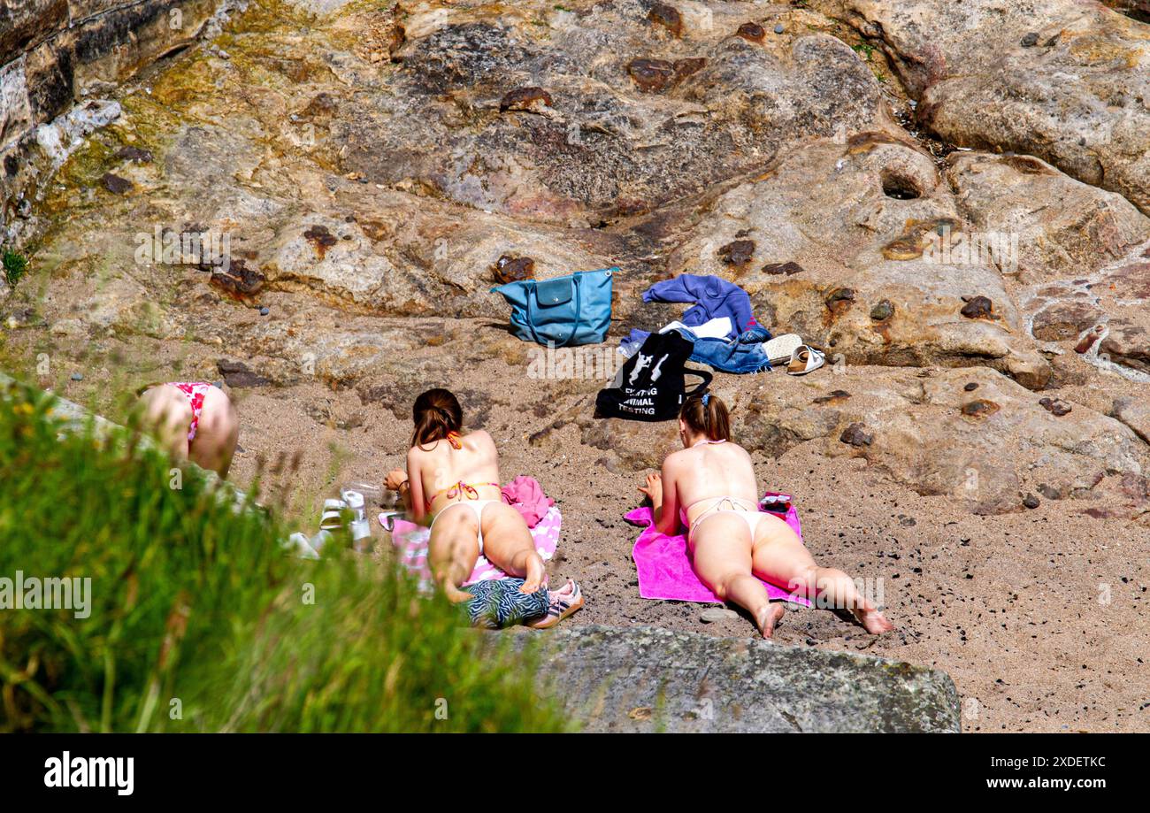 St Andrews, Fife, Schottland, Großbritannien. Juni 2024. Wetter in Großbritannien: St. Andrews in Fife, Schottland, erlebt eine wunderbare Sommerhitzewelle mit Temperaturen von 23°C. Drei junge Erwachsene Frauen verbrachten den Tag am Castle Beach und sonnten sich an einem abgeschiedenen Ort. Quelle: Dundee Photographics/Alamy Live News Stockfoto