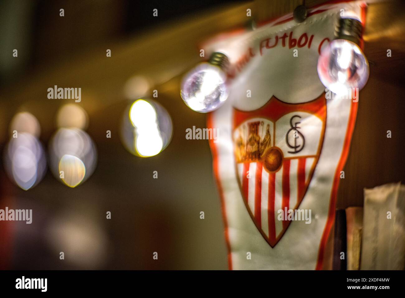 Ein verschwommenes Bild eines Sevilla FC-Banners, das von festlichen Lichtern beleuchtet wird. Ideal für Feierlichkeiten und sportliche Darstellungen. Stockfoto