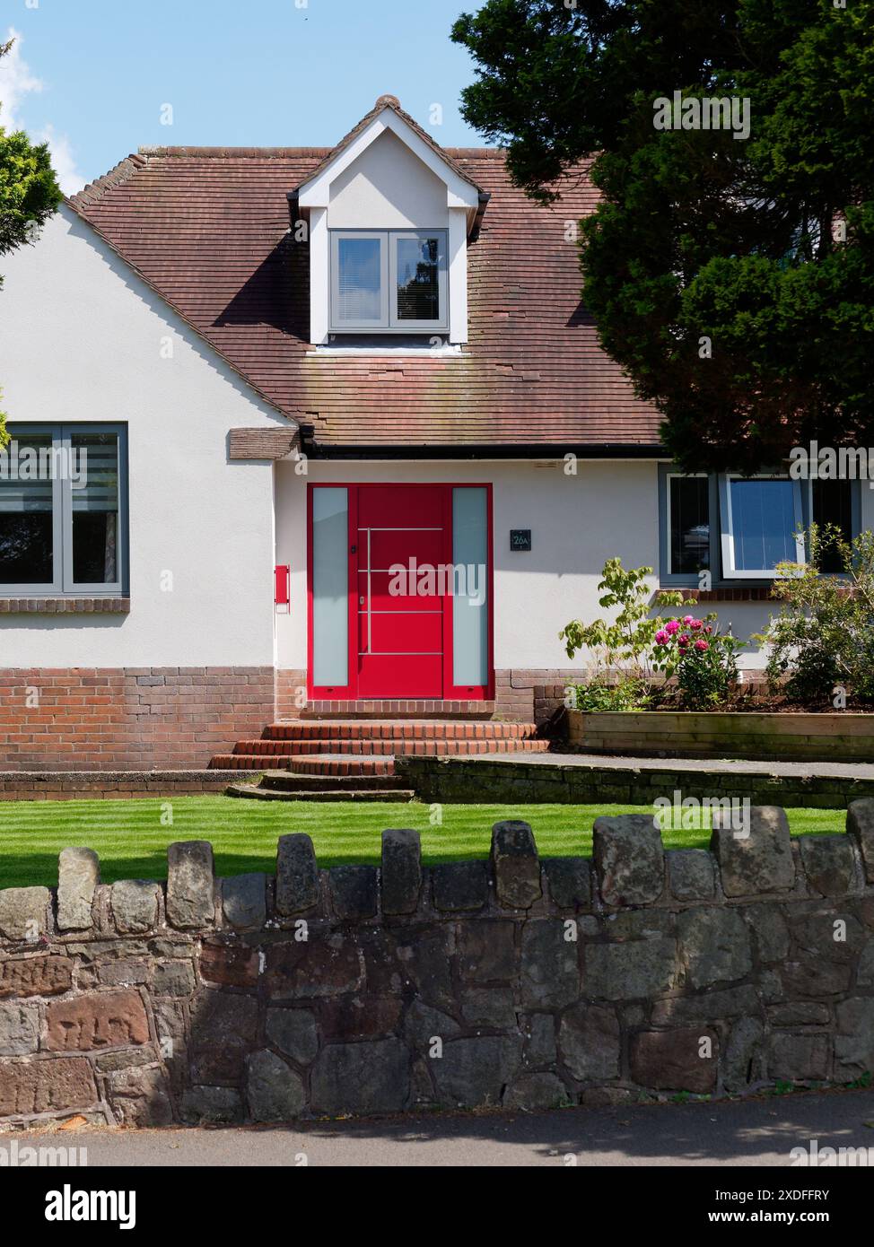 Moderner Bungalow mit Dachfenster und hellroter Eingangstür in Biddulph, Staffordshire. Juni 2024 Stockfoto