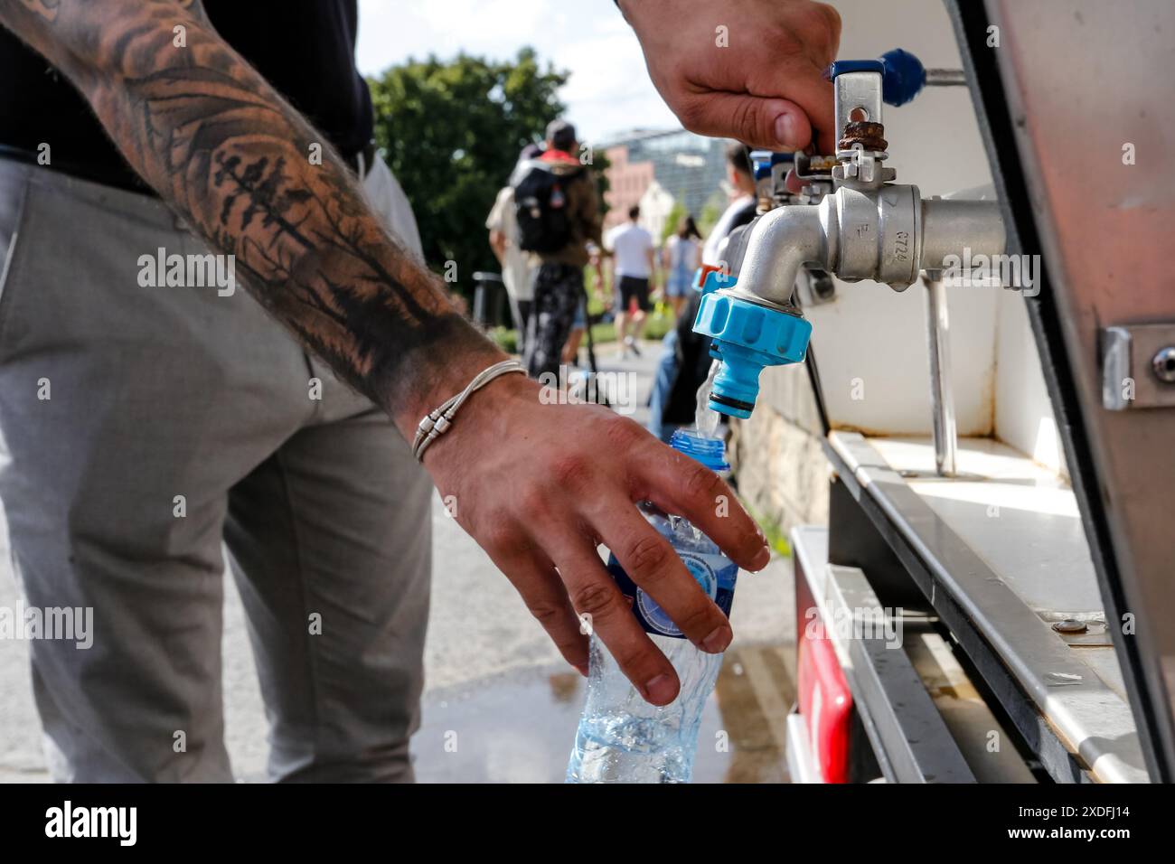 Krakau, Polen, 22. Juni 2024. Ein Mann füllt seine Flasche mit öffentlichem Wasser an einem heißen Tag während einer Veranstaltung namens „Kupala-Nacht“, eine alte slawische Tradition in einer Altstadt von Krakau. Die Kupala-Nacht ist ein altslawischer Feiertag, der auf die kürzeste Nacht des Jahres fällt. Der handgefertigte Kranz aus wilden Blumen und Kräutern, die traditionell ins Wasser geworfen wurden, war ein Omen für unverheiratete Mädchen, sich mit ihrem geliebten Menschen zu verbinden. Quelle: Dominika Zarzycka/Alamy Live News. Stockfoto