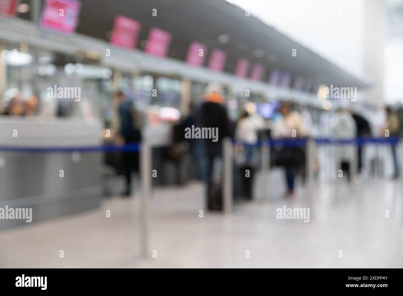 Eine verschwommene Darstellung eines belebten Check-in-Schalters am Flughafen mit zahlreichen Reisenden, die in der Schlange stehen, Gepäckwagen schieben und mit der Airline interagieren Stockfoto