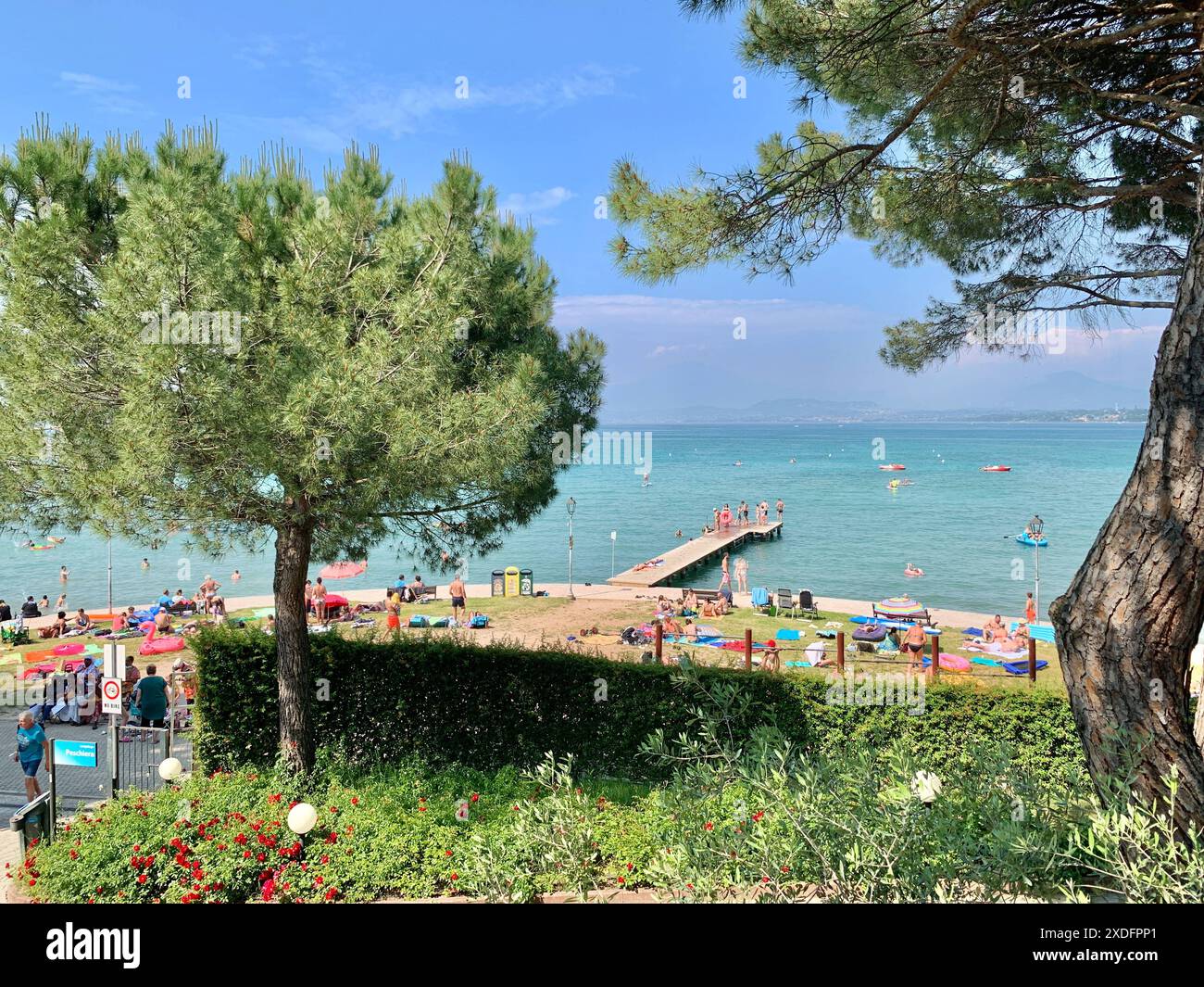 Gardasee, Peschiera del Garda, Italien, Europa, siehe, Wasser, Strand, Natur, Erholung, Tourismus, Urlaub, Sommer, kristallklares Wasser, Badegäste, Promenade, Pier, Boote, Grünflächen, Bäume, Freizeit, Aussicht, Seeufer, Entspannung, historische Stadt, Sehenswürdigkeiten, Unterkunft, Ferien, Urlaubsziel, Norditalien, Sonnenstrahlen, Naturparadies, malerische Umgebung, Reisefotografie, nachhaltiger Tourismus, Umweltschutz, Verkehr, Tourismusindustrie, lokale Wirtschaft, Wasserspiegel, Mülltrennung, Nachhaltigkeit, Erholungsgebiet, Sonnenbaden, Wassersport, Camping, Hotel, Familienurlaub, Stranda Stockfoto