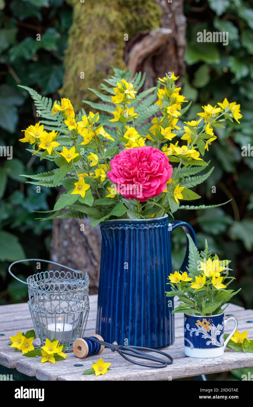 blumenarrangements mit blumenstrauß aus roter Rose, Gartenlockereien und Farnblättern im Garten Stockfoto