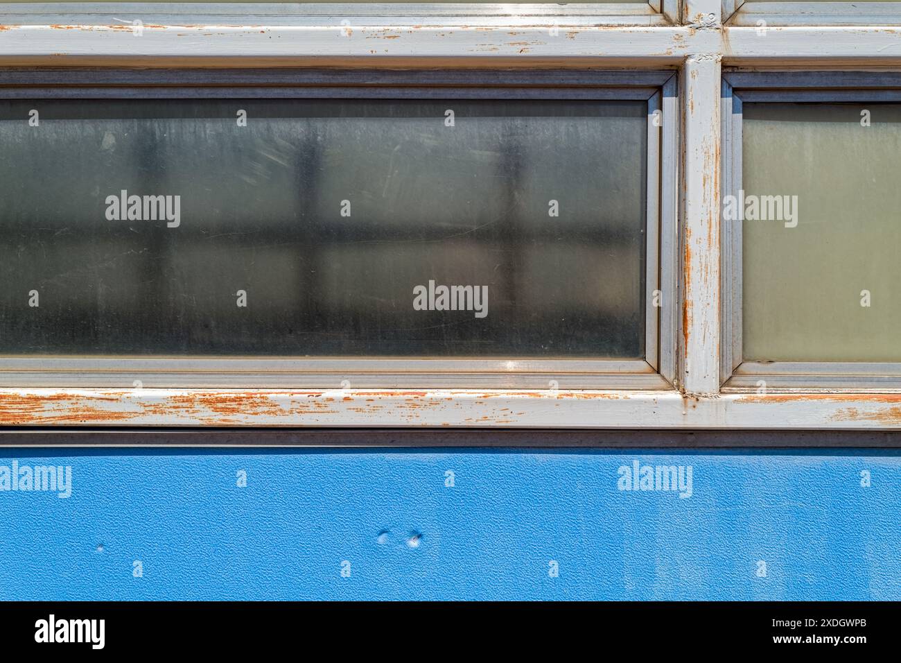Details von Fensterscheiben und blauem Metallgleis an einem verlassenen Personenbahnhof Stockfoto