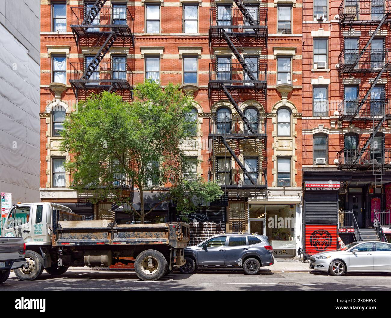 NYC Chinatown: 13 Essex Street, ein sechsstöckiges Backsteingebäude, verfügt über Geschäfte im Erdgeschoss, Gussteinverkleidungen und gestanztes Metallgesims. Stockfoto