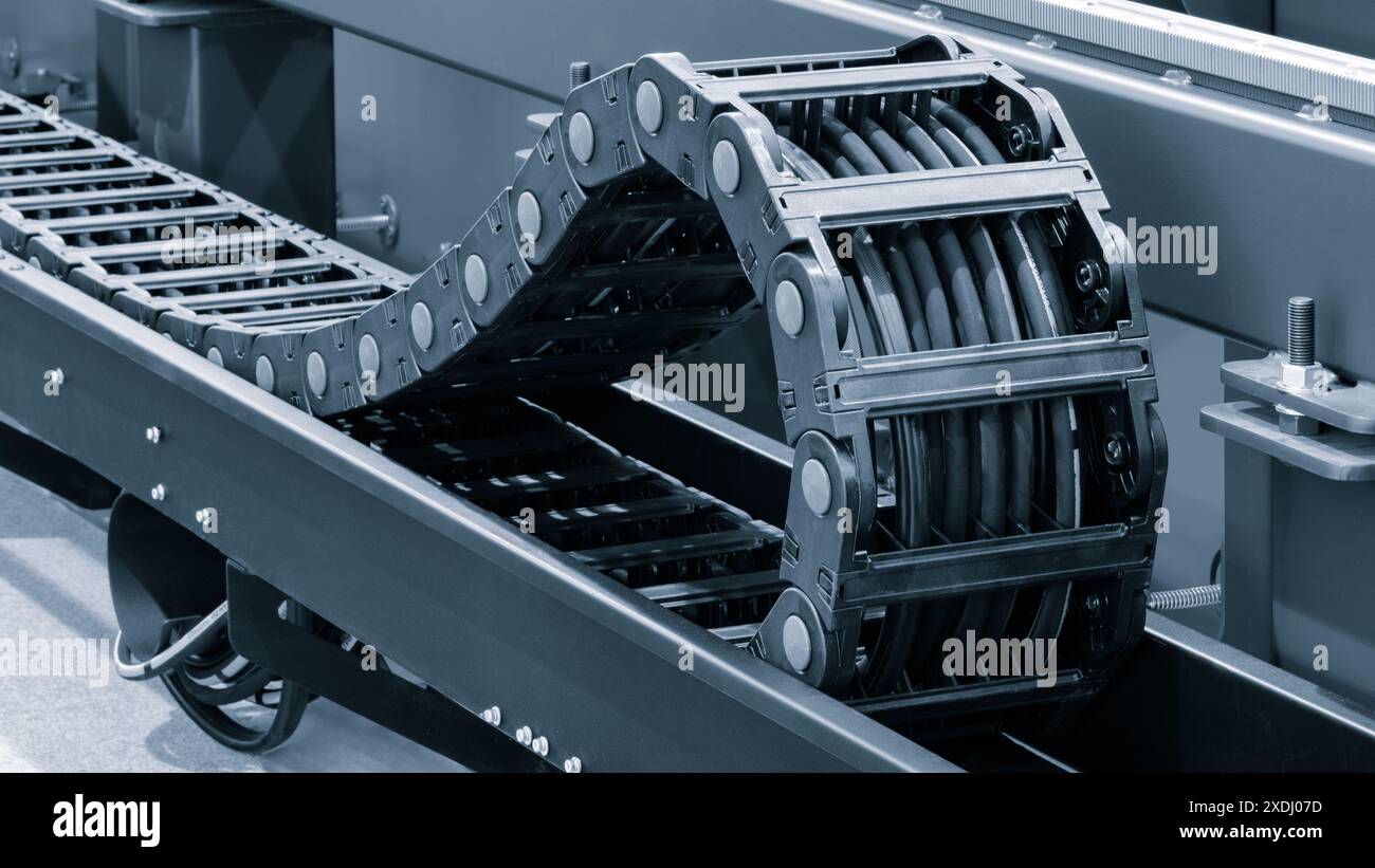 Elektrokabel in flexiblem Schutzkettengitter für Industrieförder Stockfoto