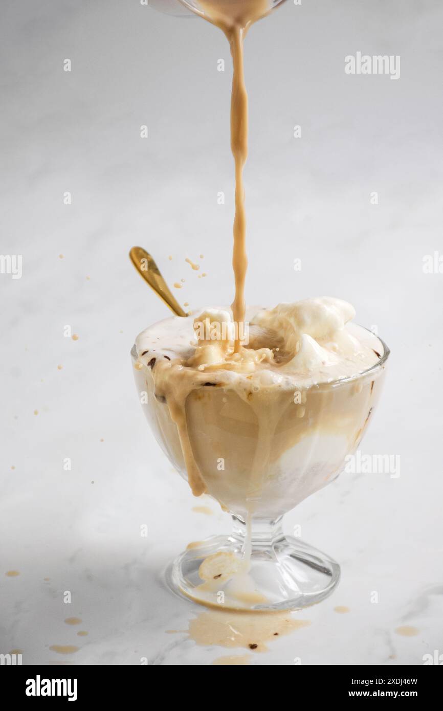 Eine Nahaufnahme des Affogato, das mit Espresso zubereitet wird, der über Vanilleeis in einer Glasschale auf weißem Hintergrund gegossen wird Stockfoto