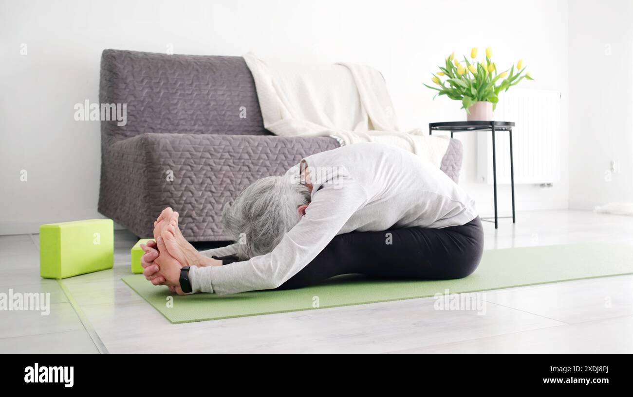 Ältere Aktive Frau, Die Zu Hause Yoga Fold Macht Stockfoto