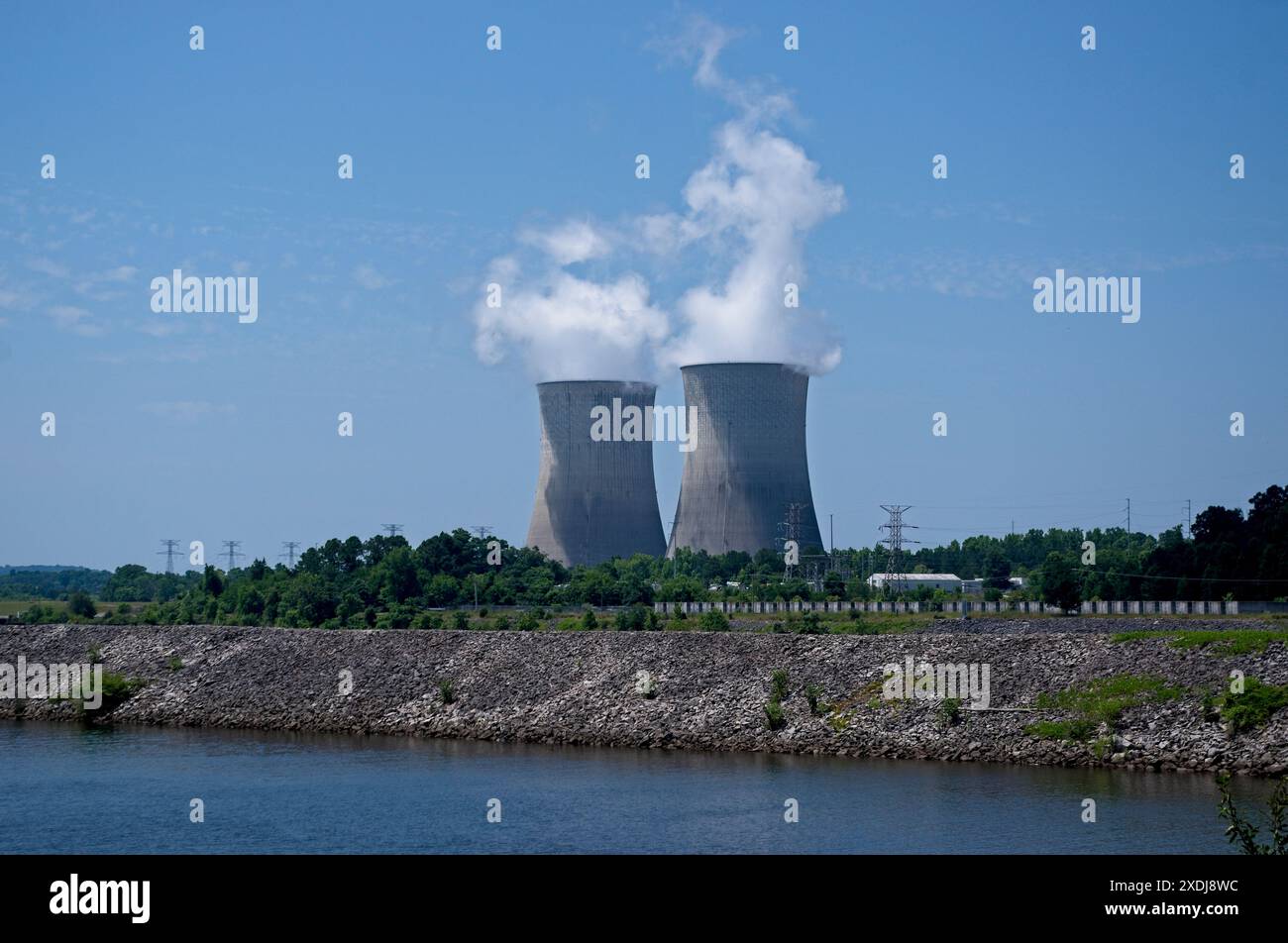 Zwei Kühltürme in einem Kernkraftwerk neben einem Wasserkörper mit aufsteigendem Dampf Stockfoto