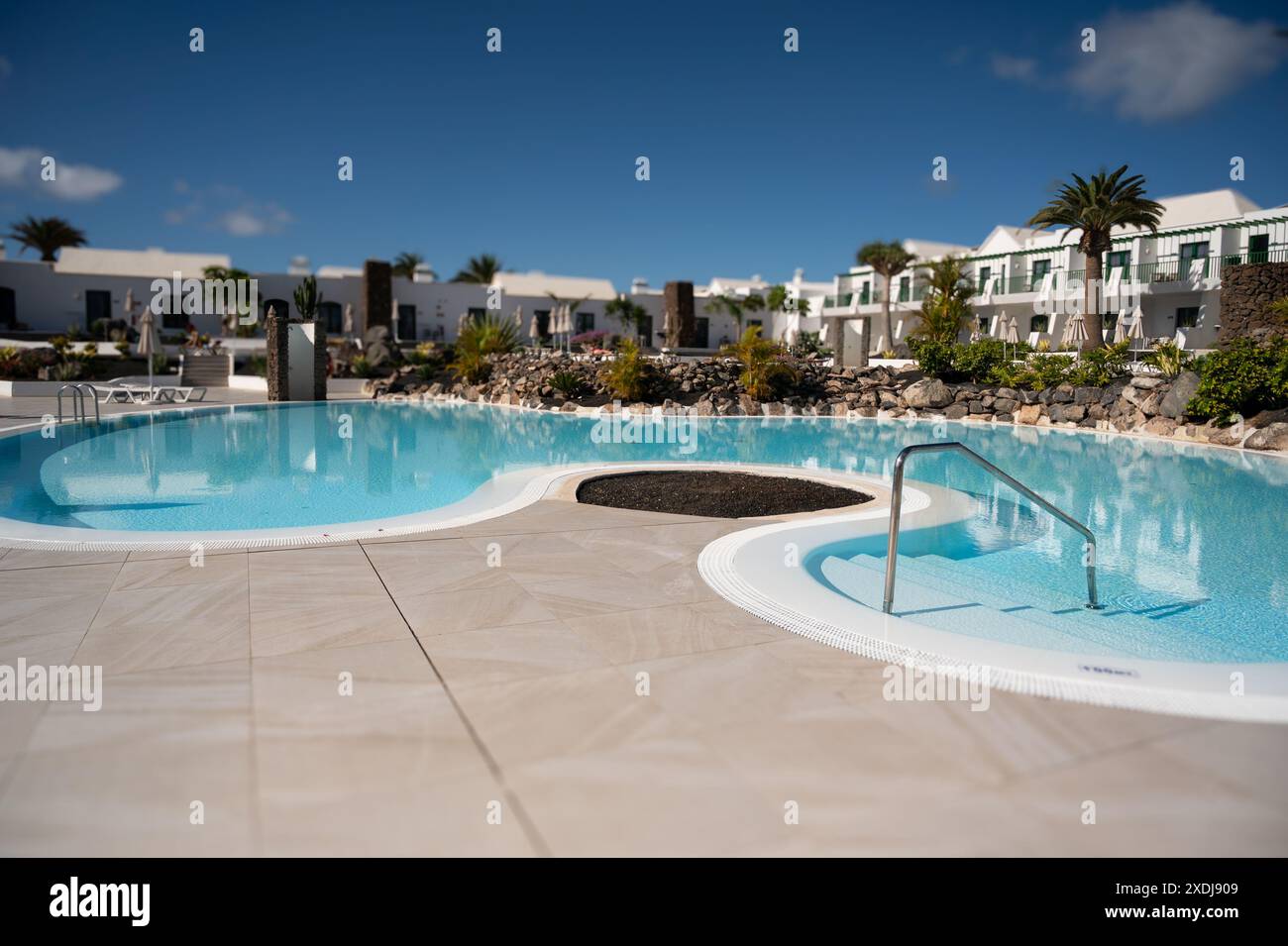 Swimmingpool, umgeben von Apartments und Palmen an klaren Tagen. Stockfoto