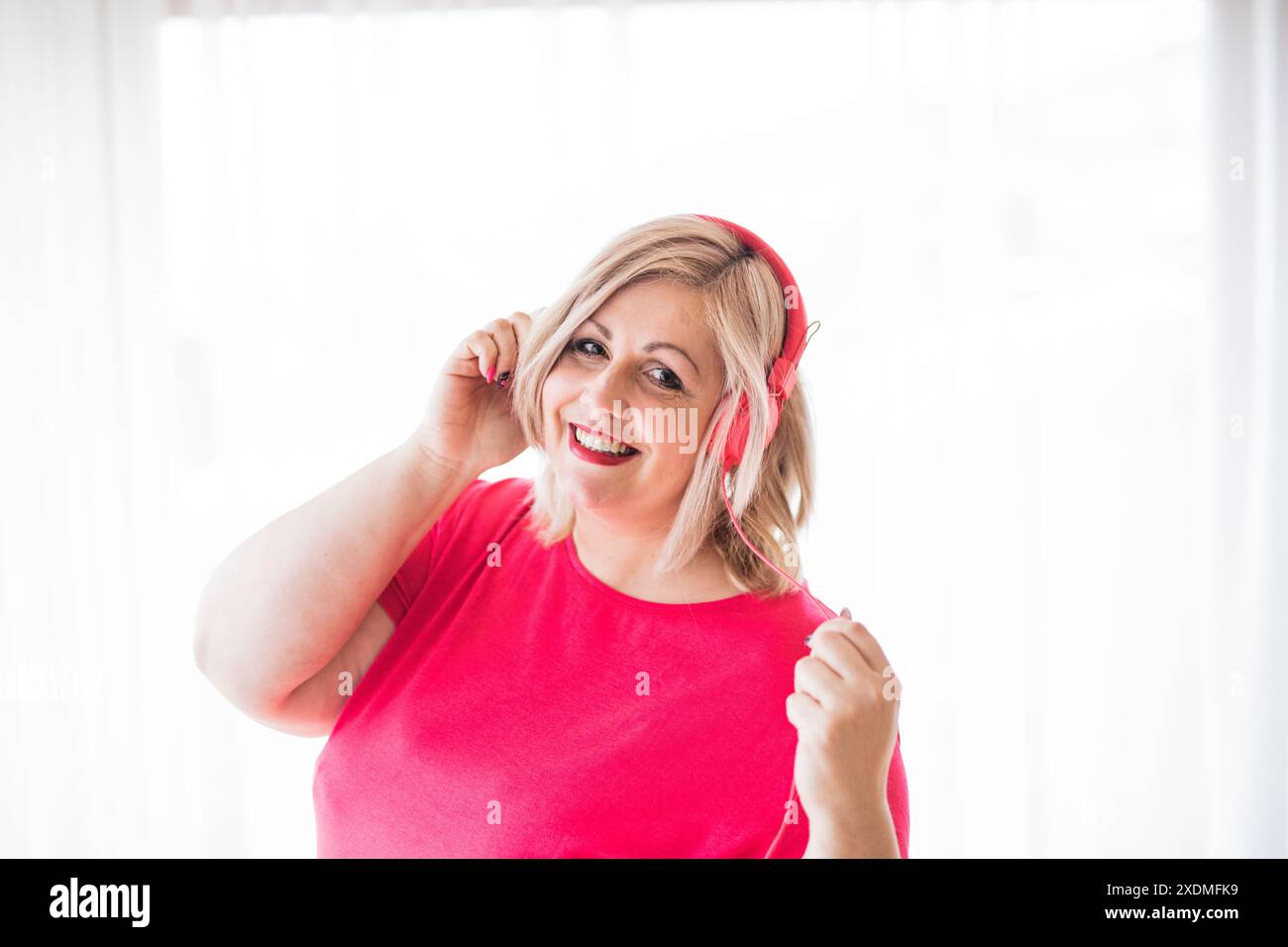 Porträt einer schönen jungen übergewichtigen Frau zu Hause, Musik über Kopfhörer hören, Spaß haben. Stockfoto