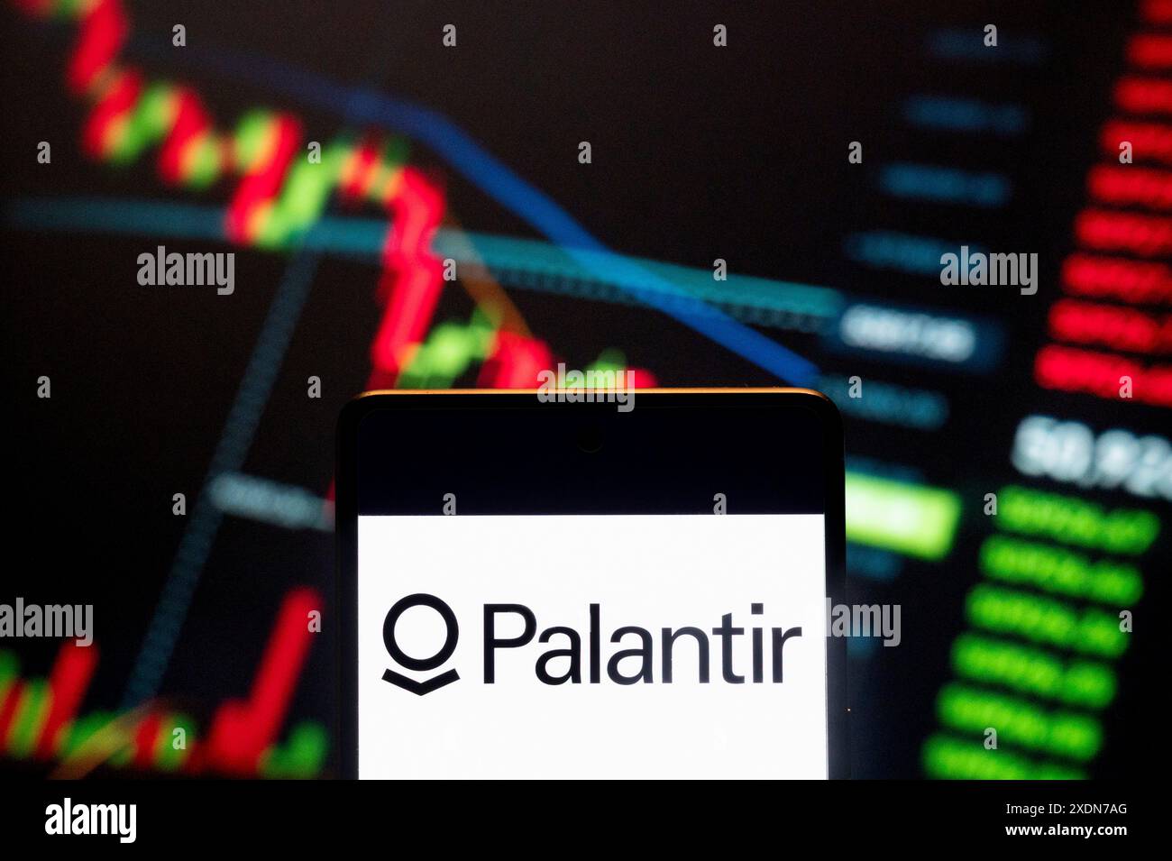 In dieser Abbildung zeigt das amerikanische Unternehmen Palantir Technologies (NYSE: PLTR), das sich auf Softwareplattformen für Big-Data-Analysen spezialisiert hat, ein Logo, das auf einem Smartphone mit einem wirtschaftlichen Börsenindex-Diagramm im Hintergrund zu sehen ist. Stockfoto