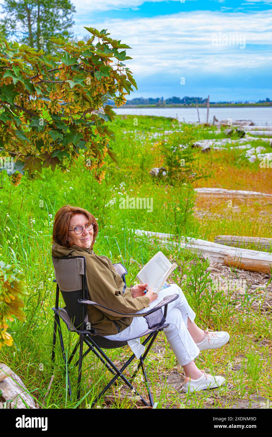 Attraktive Großmutter, die ein Buch am Fraser River in der Nähe von Vancouver, Kanada liest Stockfoto