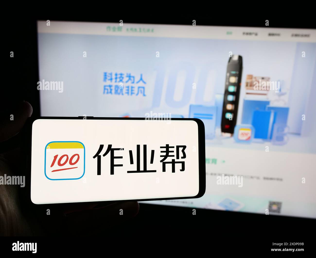 Person mit Smartphone und Logo des chinesischen Online-Bildungsplattform-Unternehmens Zuoyebang vor der Website. Schwerpunkt auf dem Display des Telefons. Stockfoto