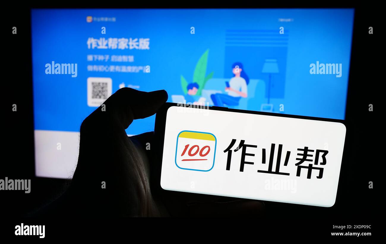 Person, die ein Mobiltelefon mit dem Logo des chinesischen Online-Bildungsplattform-Unternehmens Zuoyebang vor der Webseite hält. Schwerpunkt auf dem Display des Telefons. Stockfoto
