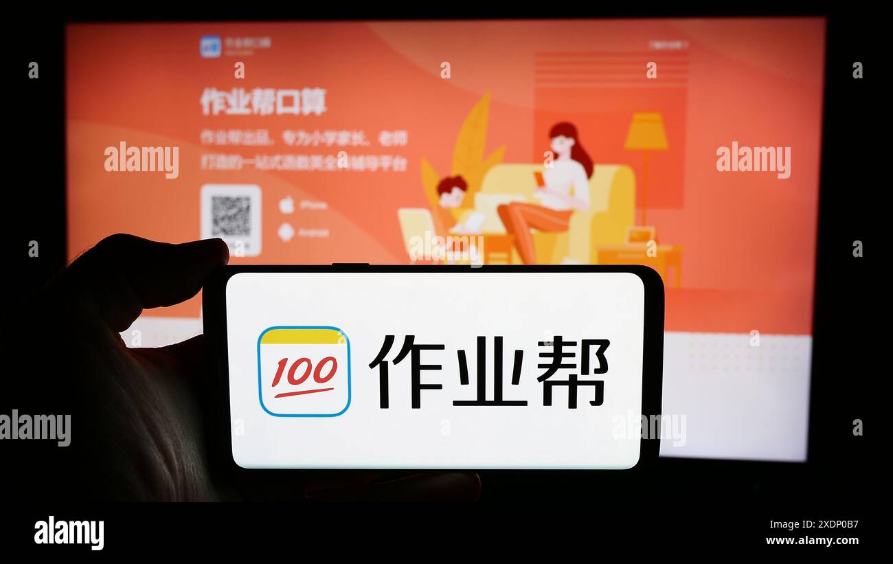 Person, die ein Mobiltelefon mit dem Logo des chinesischen Online-Bildungsplattform-Unternehmens Zuoyebang vor der Business-Website hält. Schwerpunkt auf dem Display des Telefons. Stockfoto