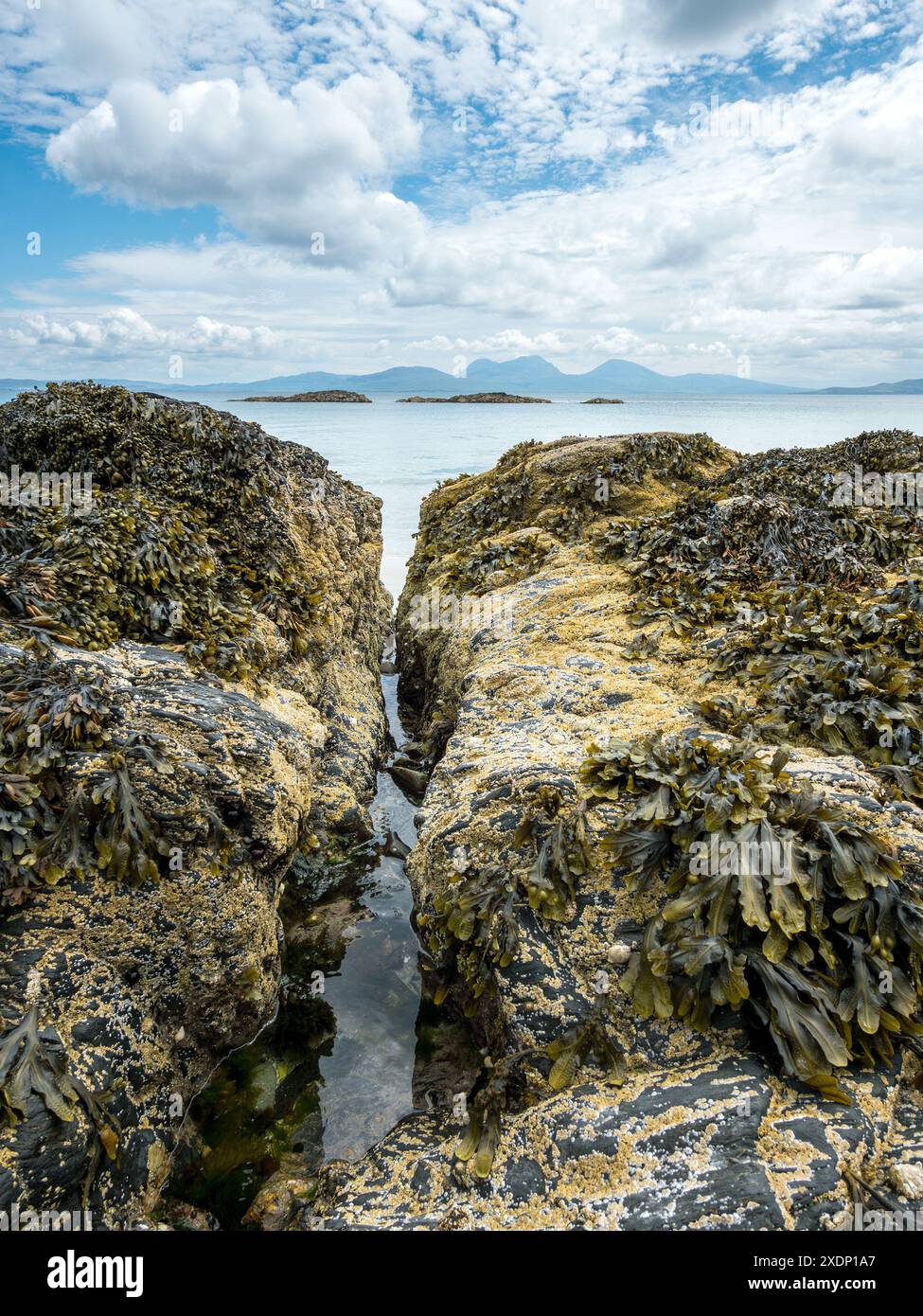 Der Paps of Jura ist am Horizont vom Port A Chapuill Strand auf der nahegelegenen Insel Colonsay in den Inneren Hebriden in Schottland, Großbritannien, zu sehen Stockfoto