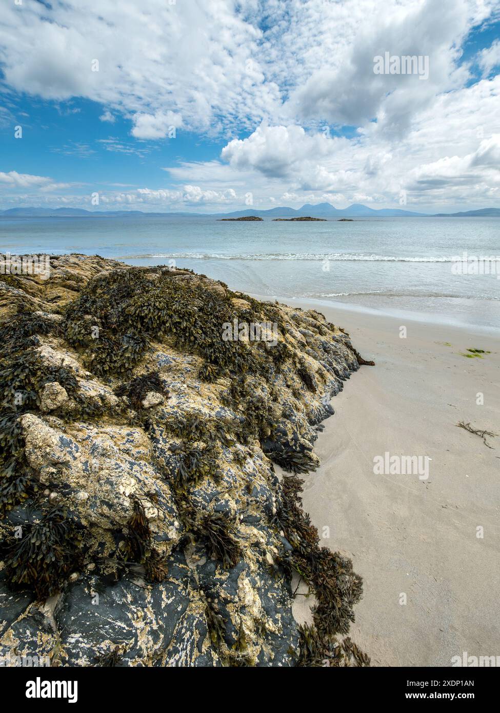 Der Paps of Jura ist am Horizont vom Port A Chapuill Strand auf der nahegelegenen Insel Colonsay in den Inneren Hebriden in Schottland, Großbritannien, zu sehen Stockfoto