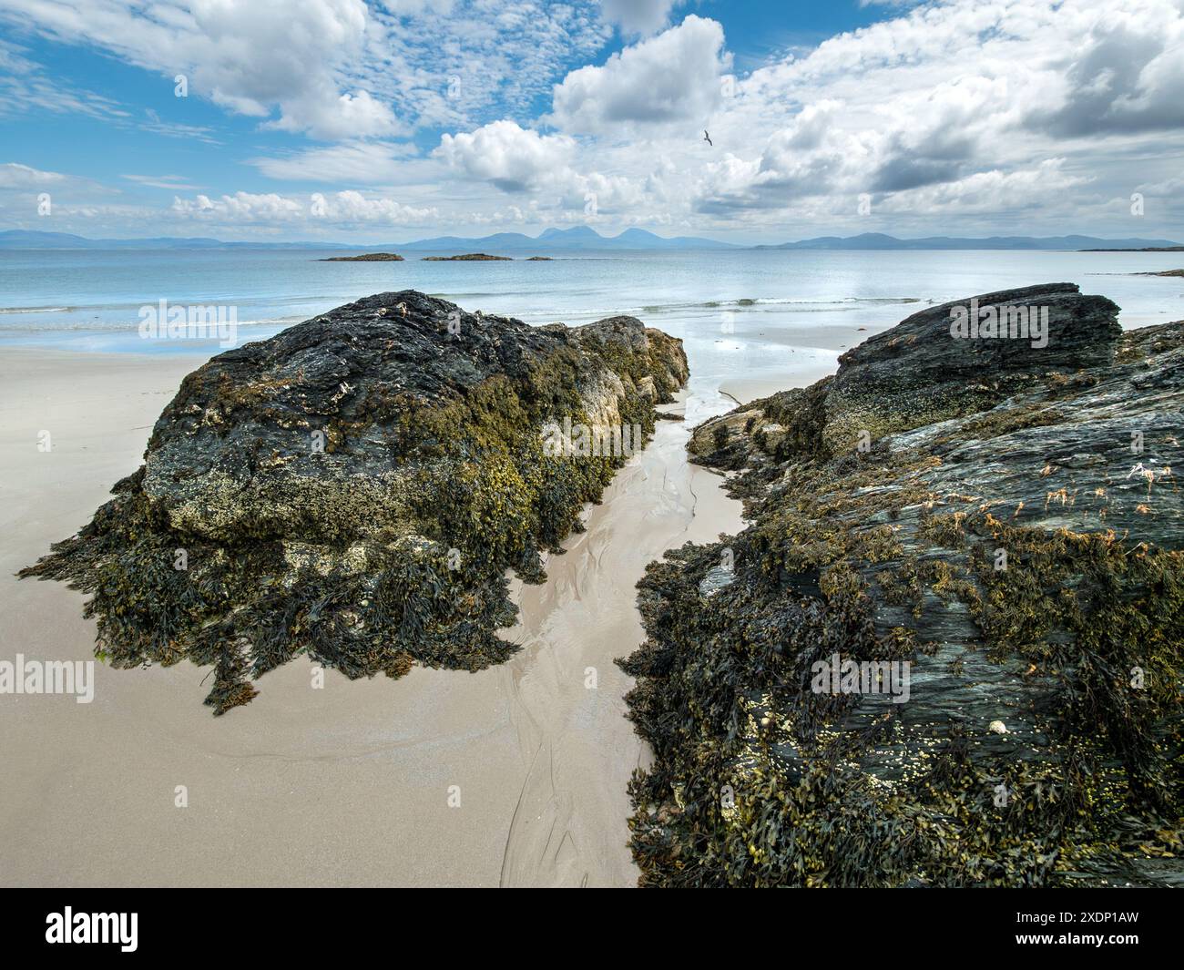Der Paps of Jura ist am Horizont vom Port A Chapuill Strand auf der nahegelegenen Insel Colonsay in den Inneren Hebriden in Schottland, Großbritannien, zu sehen Stockfoto