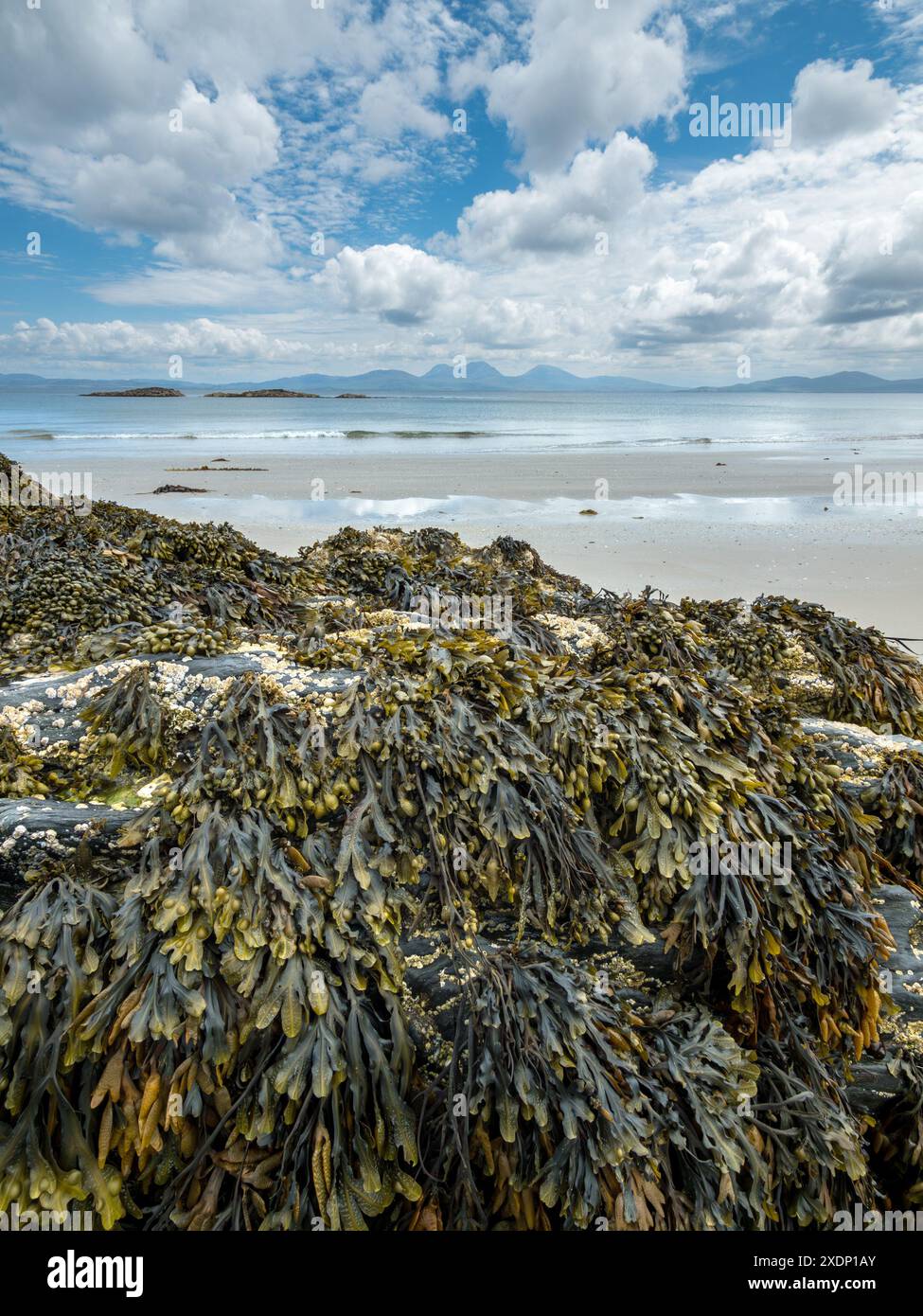 Der Paps of Jura ist am Horizont vom Port A Chapuill Strand auf der nahegelegenen Insel Colonsay in den Inneren Hebriden in Schottland, Großbritannien, zu sehen Stockfoto