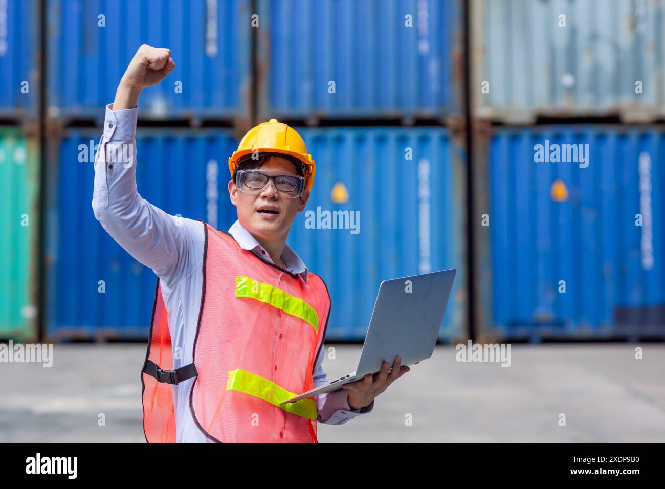 Siegererfolg männlicher Arbeiter, der in der Logistikbranche für Frachtschifffahrt mit der Faust aufsteigt. Stockfoto