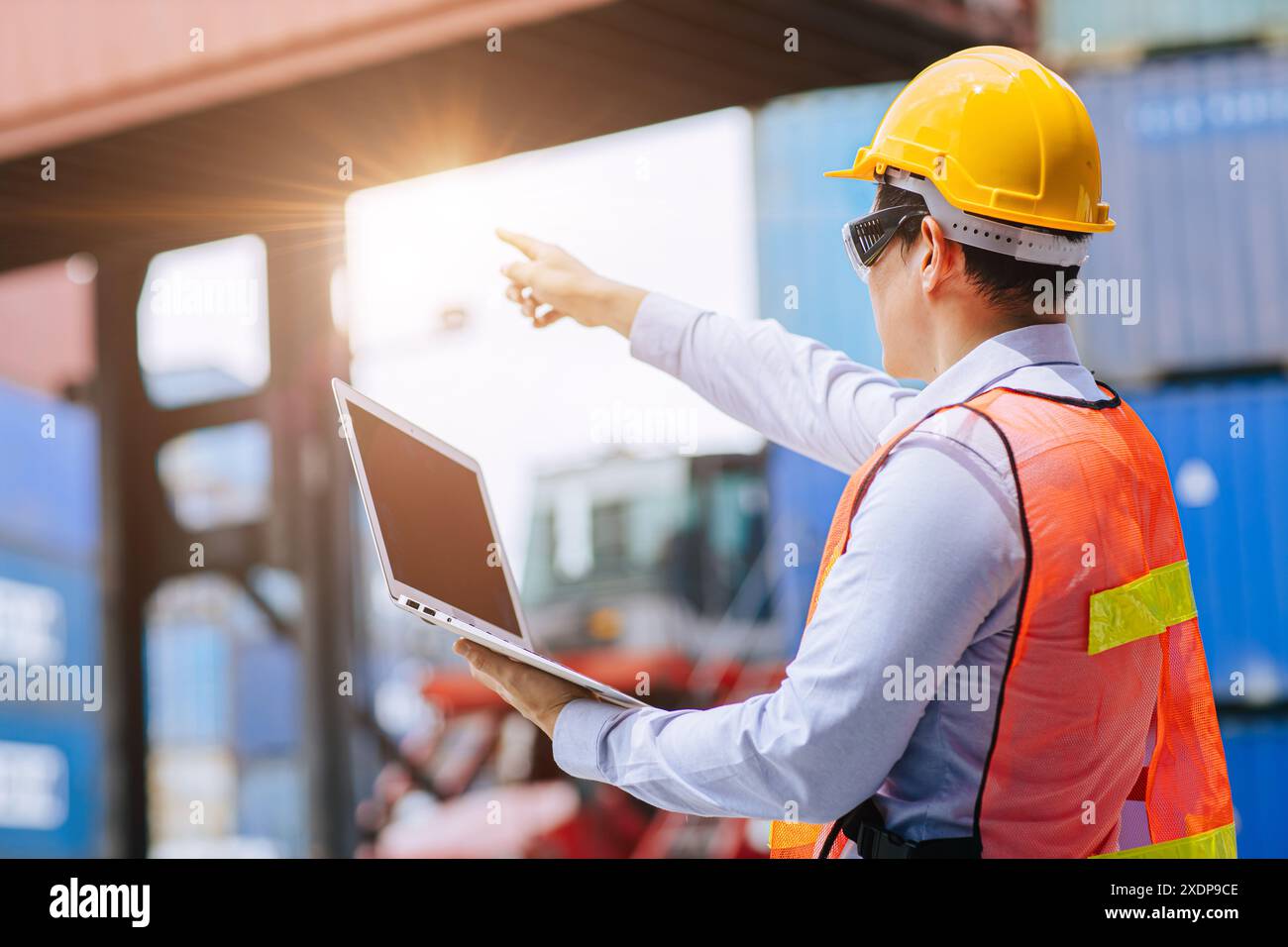Erfolgreicher männlicher Arbeiter, der bei der Auftragskontrolle in der Logistikbranche für den Frachttransport hoch steht. Stockfoto