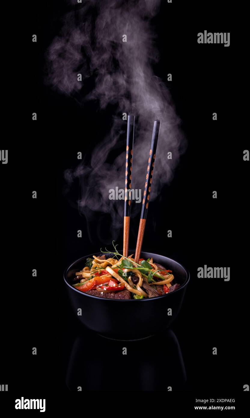 Udon nudeln Wokgemüse mit Tiger Garnelen und Gemüse im Wok kochen Pan auf dunklem Hintergrund Stockfoto