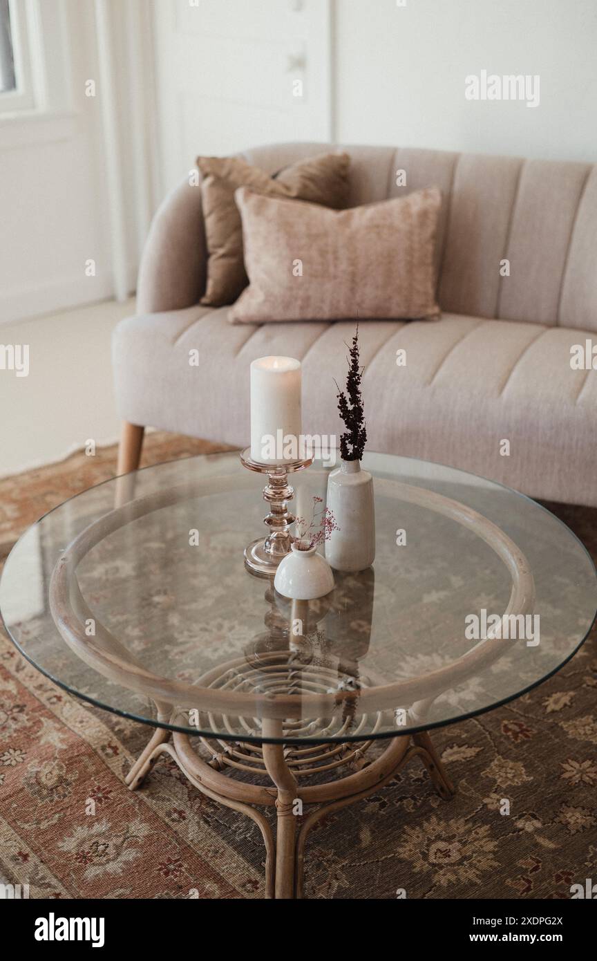 Minimalistisches Wohnzimmer mit beigefarbenem Sofa und Glaszimmertisch. Stockfoto