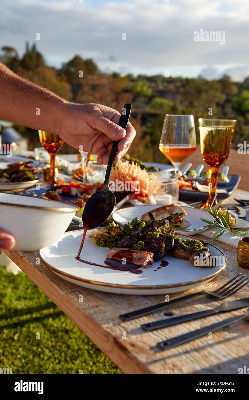 Der Koch verleiht gegrillten Lammkoteletts den letzten Schliff der Sauce Stockfoto