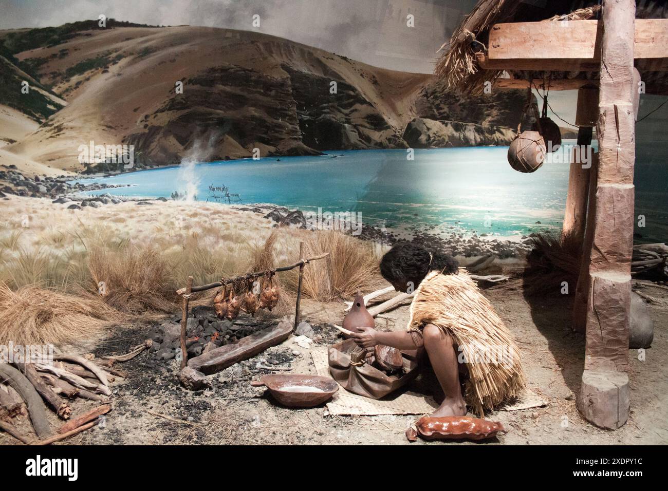 Ein Diorama des Maori-Lebens im Canterbury Museum, das einen Mann zeigt, der vor seiner Hütte Essen kocht. Körniges Bild, das bei verfügbarem Licht aufgenommen wird. Stockfoto