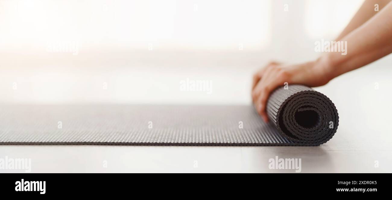 Person, die Yoga-Matte auf dem Boden aufrollen lässt Stockfoto