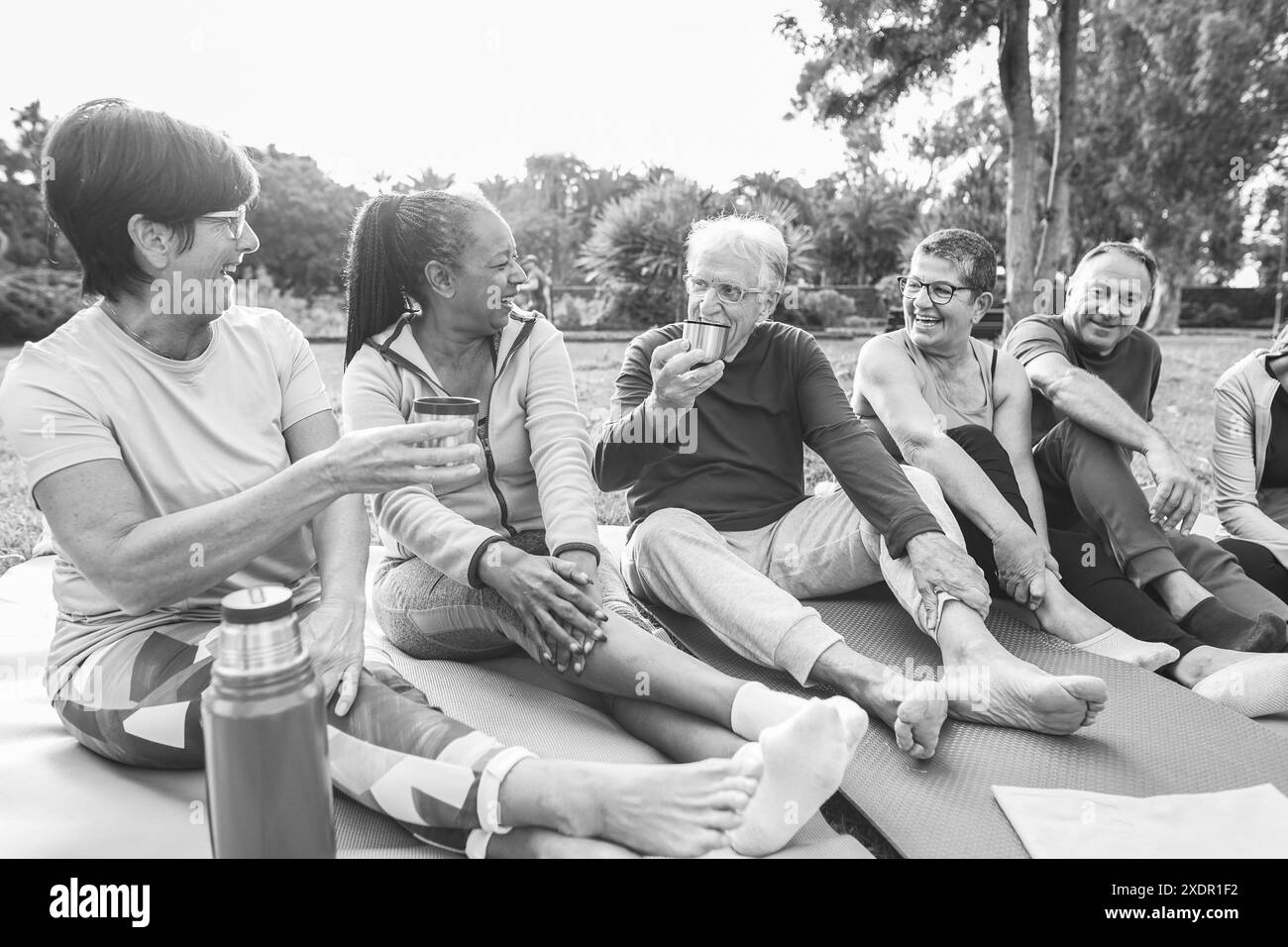 Seniorenfreunde chatten und trinken heißen grünen Tee nach dem Yoga-Kurs im Freien - gesunder Lebensstil für Erwachsene Menschen und Sportkonzept - Fokus auf afrika Stockfoto