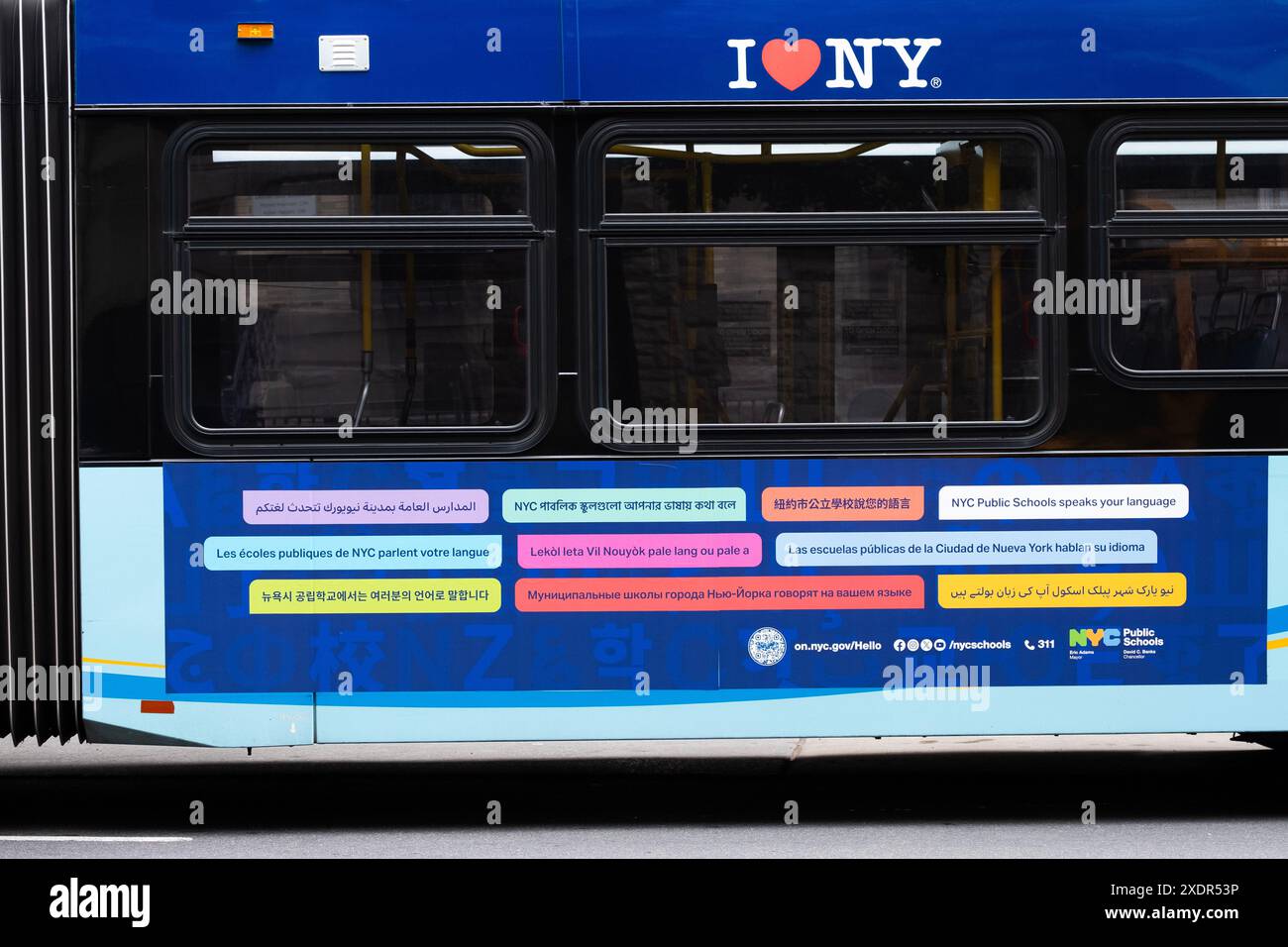 Ein Schild an der Seite eines Brooklyn-Busses, das besagt, dass die öffentlichen Schulen von New York City Ihre Sprache sprechen. 11 Sprachen werden angezeigt. Stockfoto