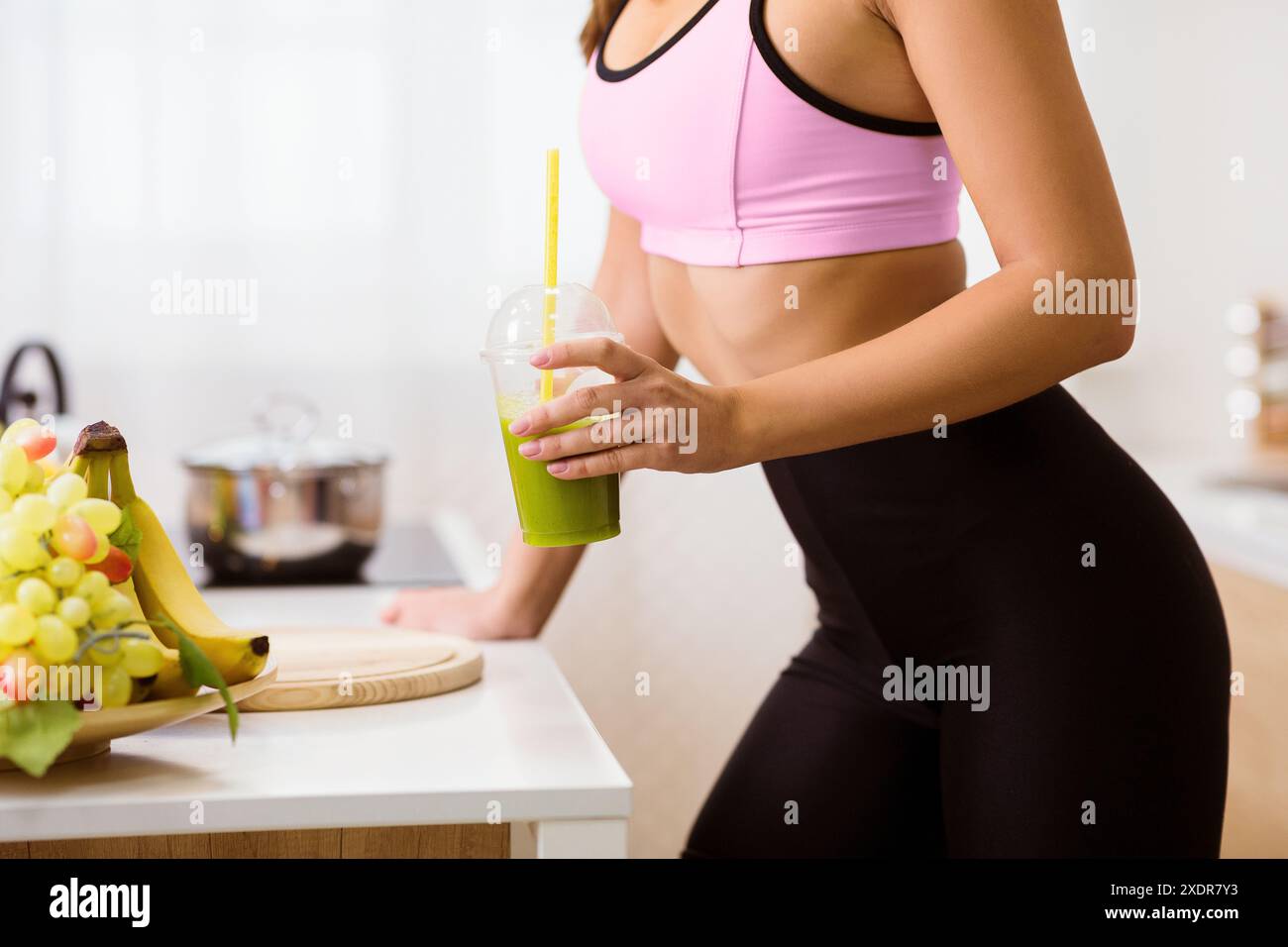 Frau trinkt Green Smoothie in der Küche Stockfoto