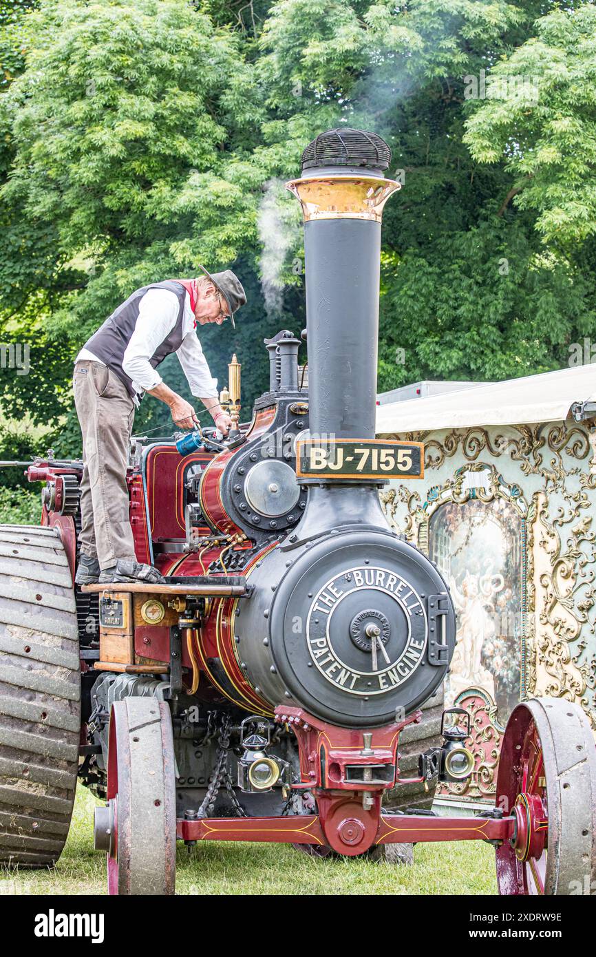 BROADCHALKE, WILTSHIRE, UK, 24. Juni 2024, Mann in historischer Kleidung an einer Dampfmaschine beim Chalke History Festival, dem führenden Geschichtsfestival Großbritanniens am Eröffnungstag, das Hunderttausende von Geschichtsbegeisterten anzieht (darunter Zehntausende von Schulkindern während des speziellen Schulfestivals an den ersten beiden Tagen). John Rose/Alamy Live News Stockfoto