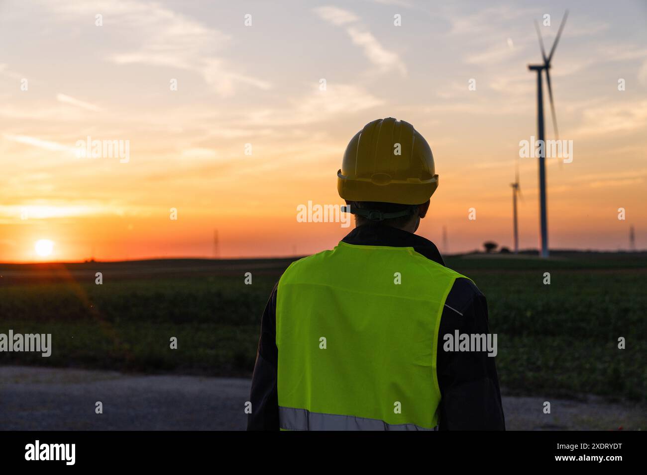 Arbeiter schaut sich Windräder bei Sonnenuntergang an Stockfoto