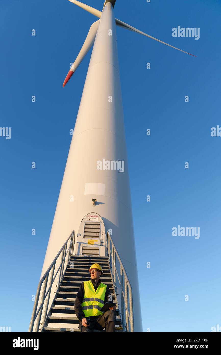 Techniker mit digitalem Tablet neben Windkraftanlage. Stockfoto