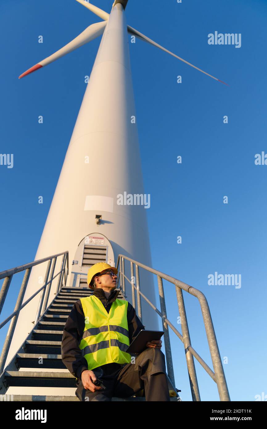 Techniker mit digitalem Tablet neben Windkraftanlage. Stockfoto