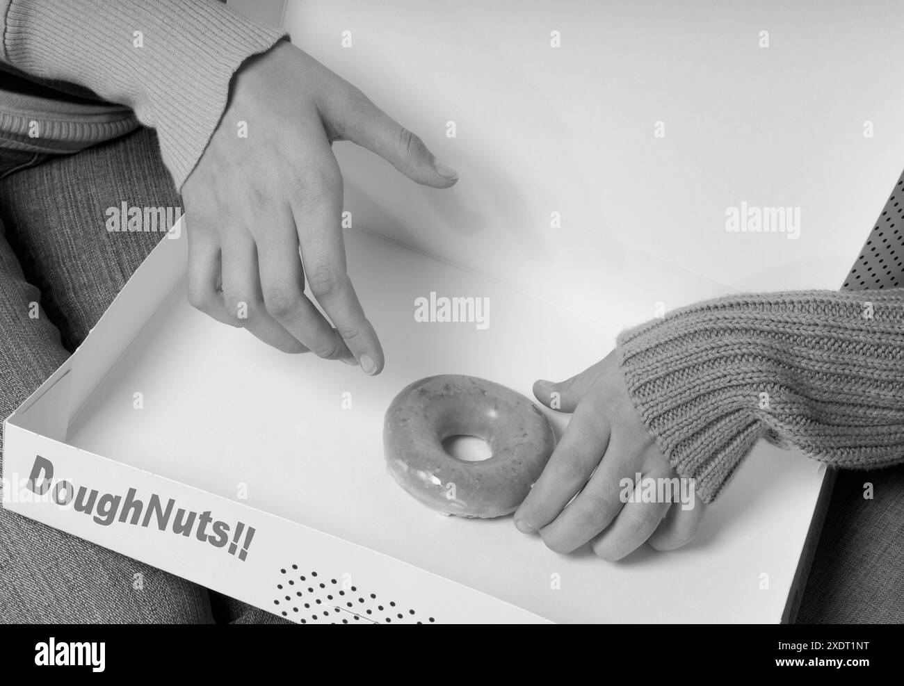 Zwei Mädchenhände greifen nach dem letzten Donut in einer Box und symbolisieren spielerische Wettkämpfe und eine gemeinsame Liebe zu süßen Leckereien. USA Stockfoto