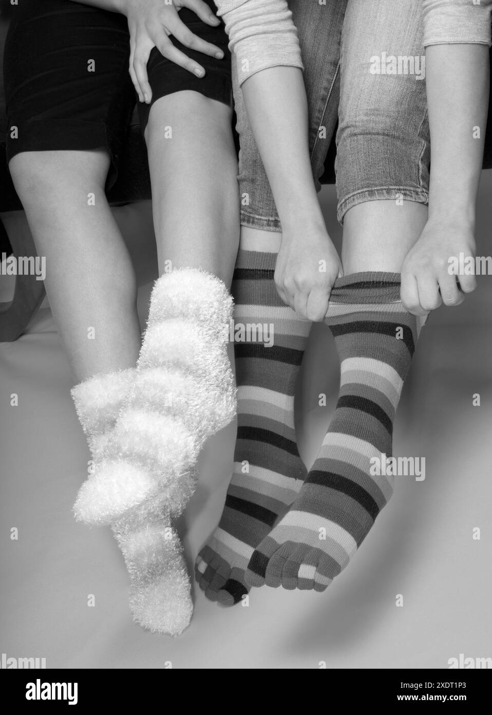 Beine und Füße von zwei Teenager-Mädchen in bunten Socken. USA Stockfoto