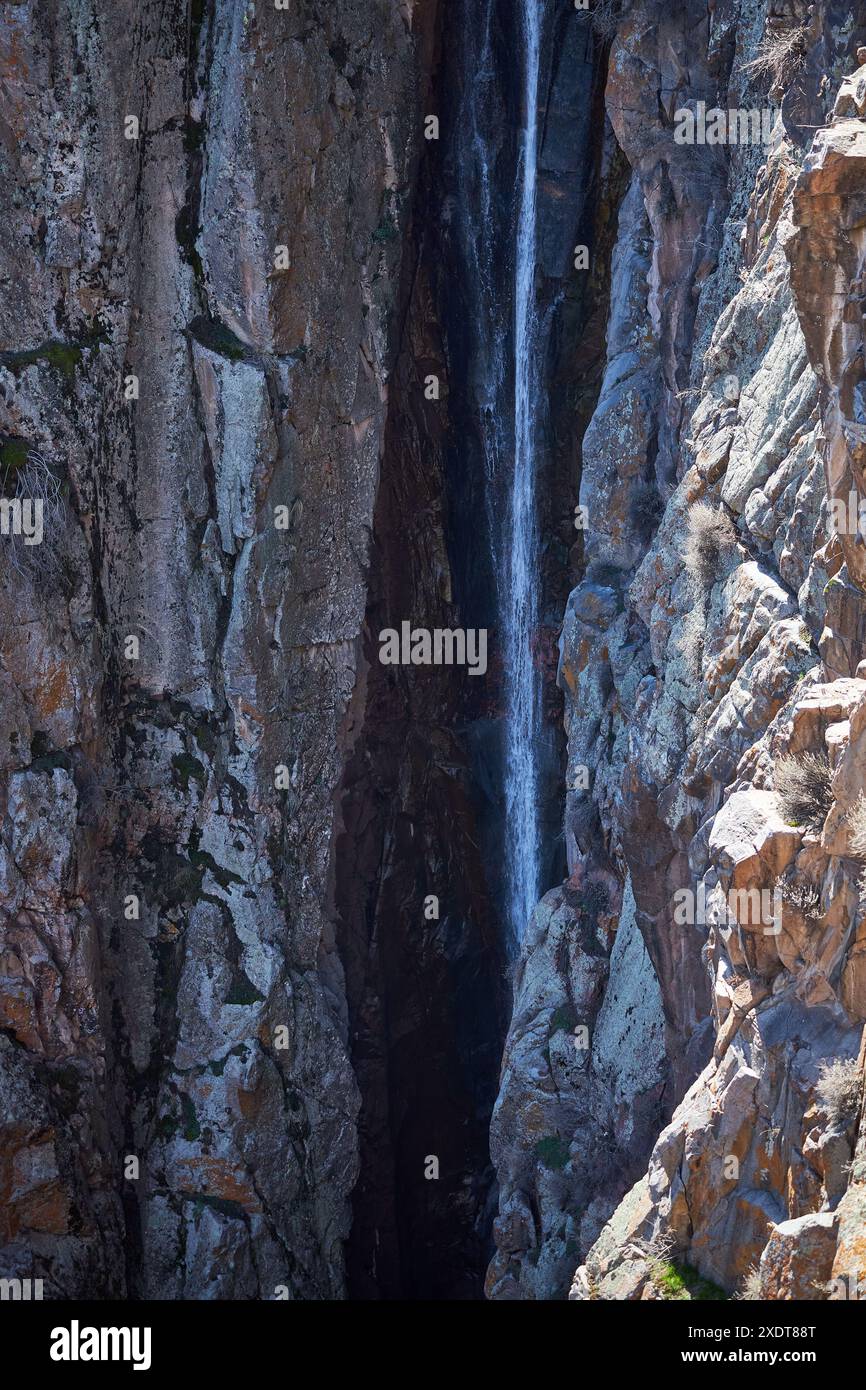 Bachlauf zwischen steilen Klippen. Kleiner Wasserfall in Felsen, Nahaufnahme. Wasserstrom, Gebirgsbach fließt. Frühjahrsschmelze der Gletscher im gebirgigen Ar Stockfoto