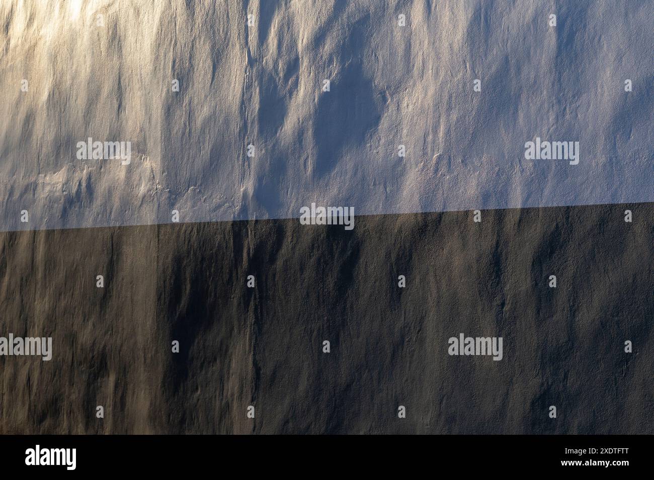 Nahaufnahme einer sauberen und unebenen Wand in weiß und Schwarz. Schönes Seitenlicht erzeugt weiche Schatten. Abstrakter texturierter Hintergrund, Kopierraum. Stockfoto