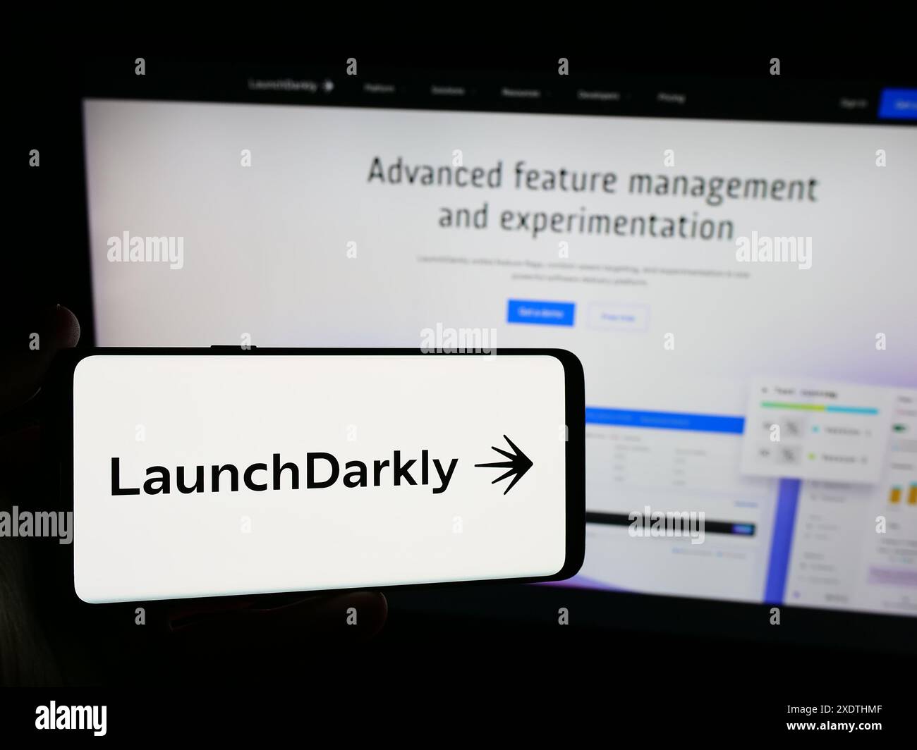 Person mit Smartphone und Logo des US-Softwareunternehmens Catamorphic Co. (LaunchDarkly) vor der Website. Schwerpunkt auf dem Display des Telefons. Stockfoto